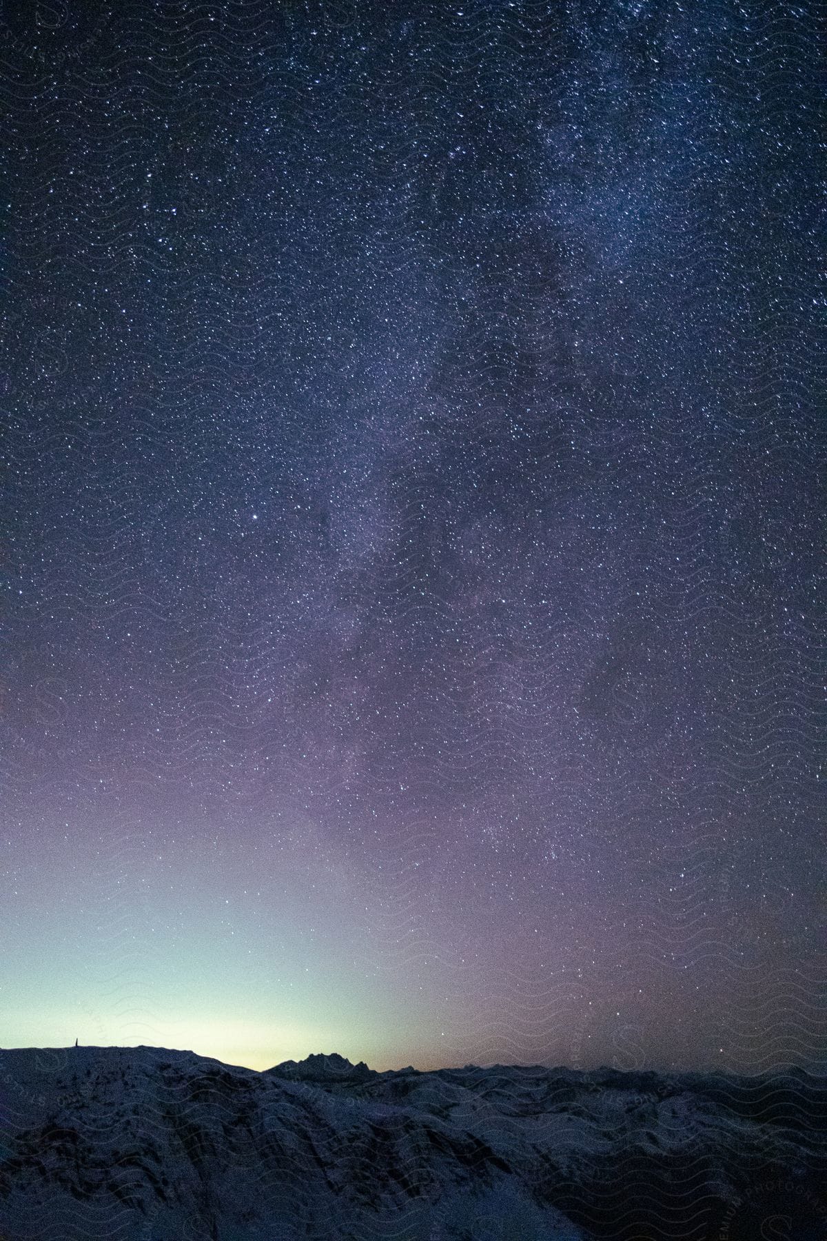 Moonlit snowcovered mountains reveal a starry night sky