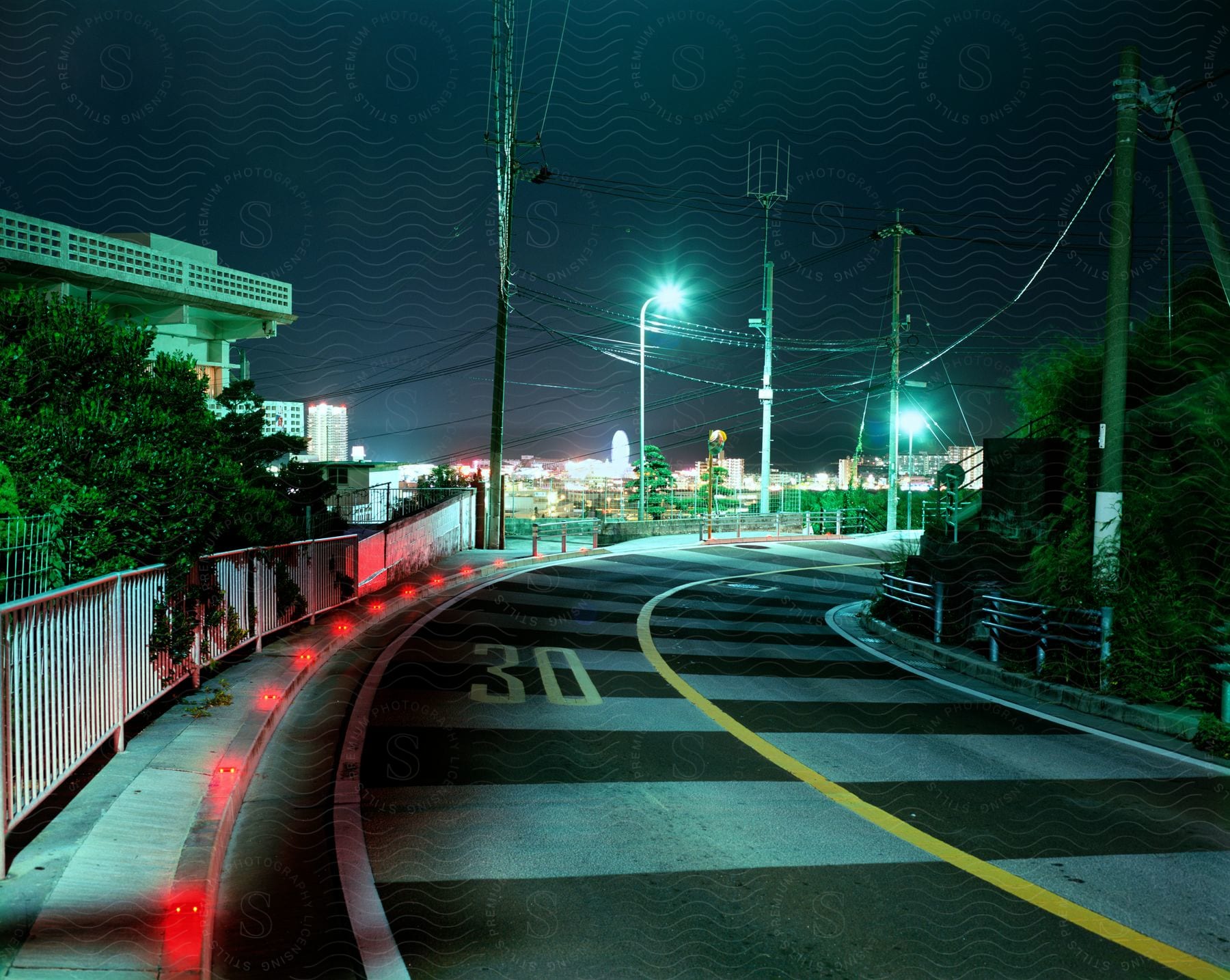 A road with white lines and the number thirty a building on the side and red lights along the road