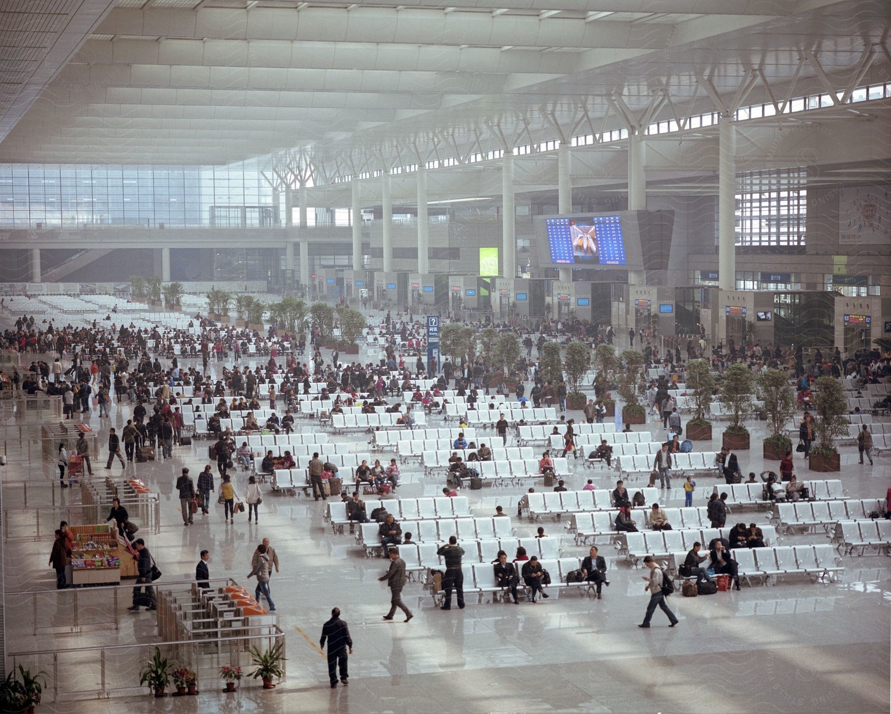 A crowded airport terminal with people seated