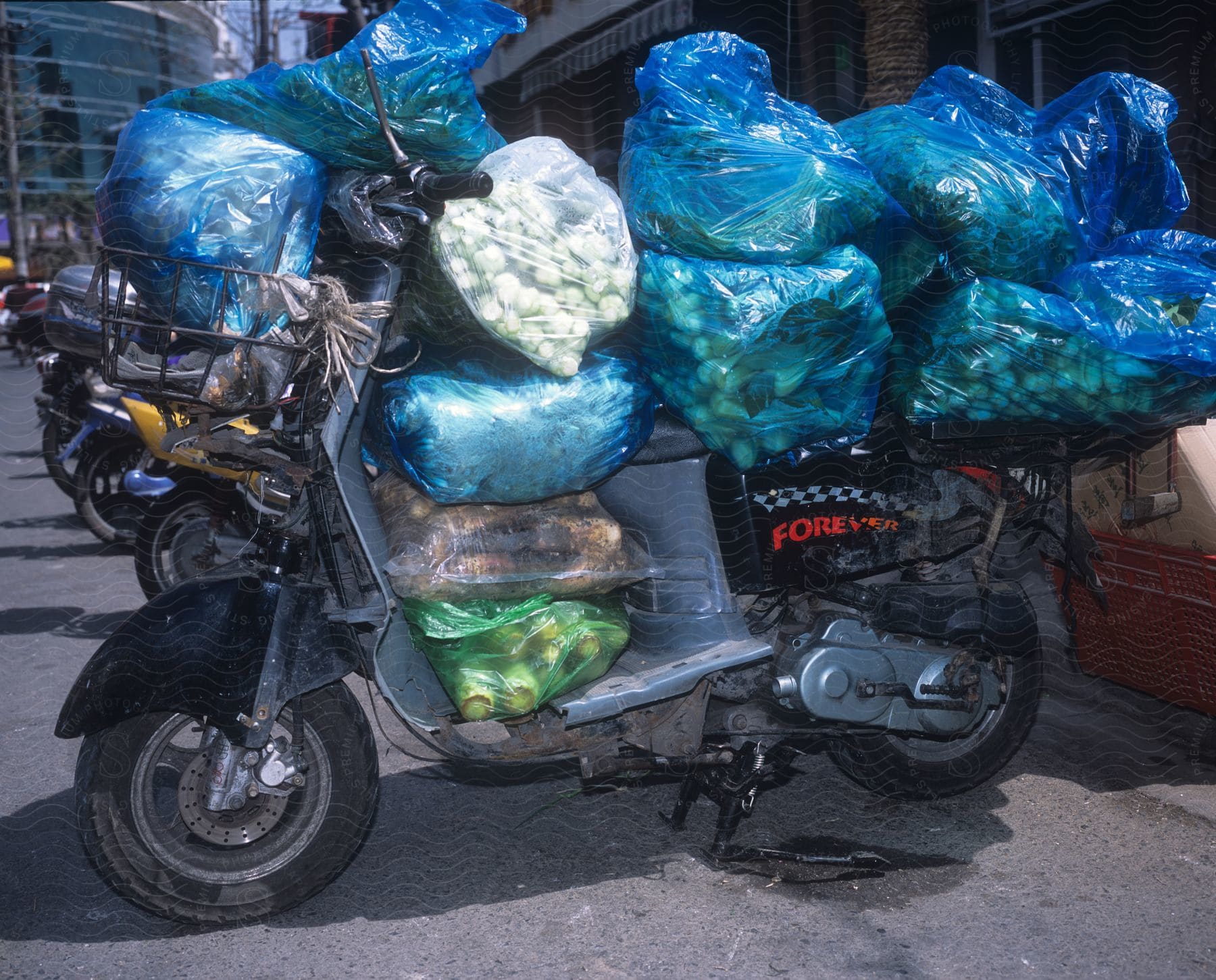 Plastic bags full of fruit and vegetables piled up over a motorcycle parked on the street