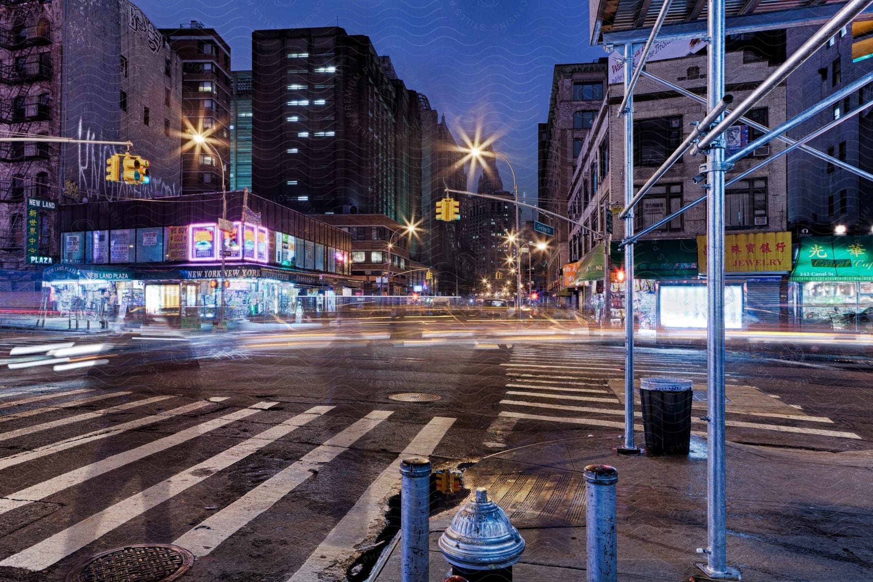 A blurred cityscape at night with traffic on the road and peoples shadows on the street