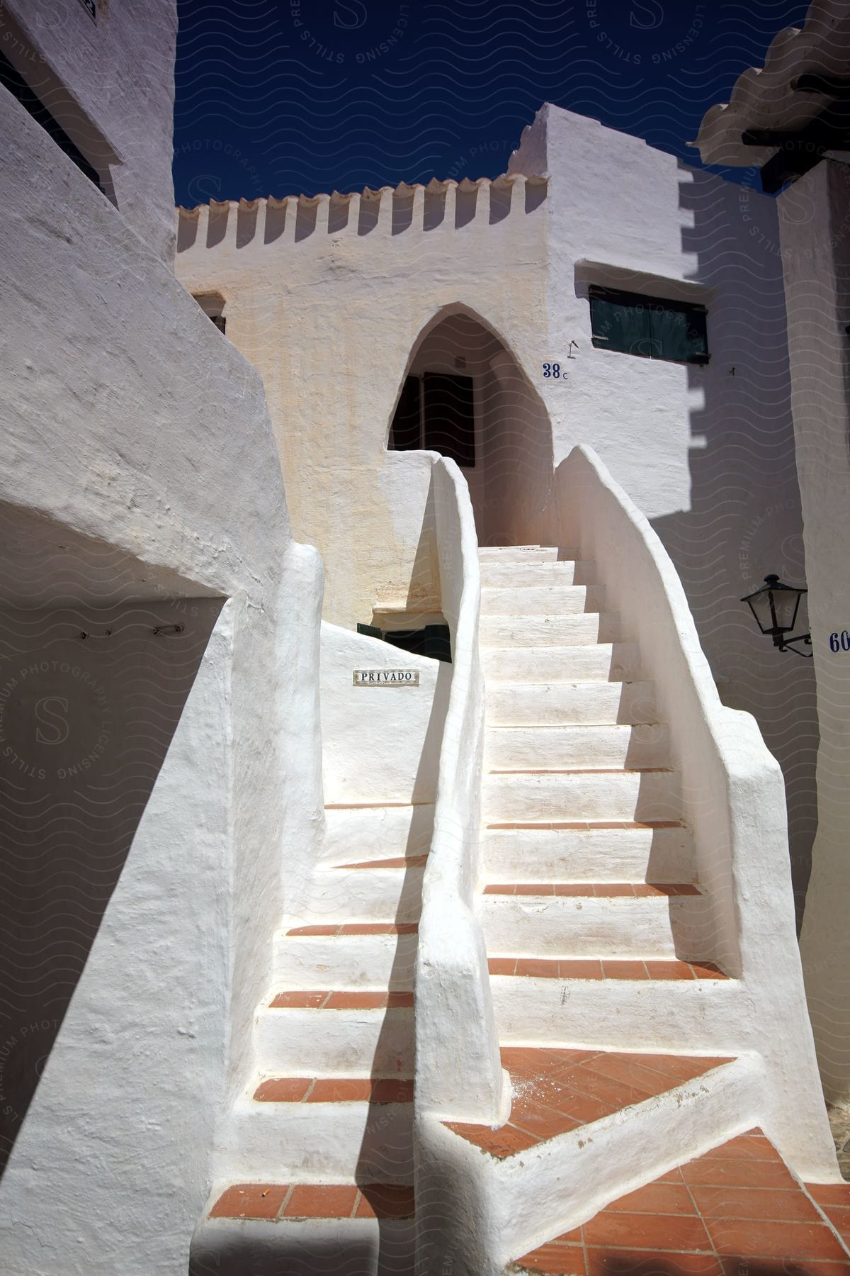 A greek vacation home with a white exterior and a staircase leading to its entrance door