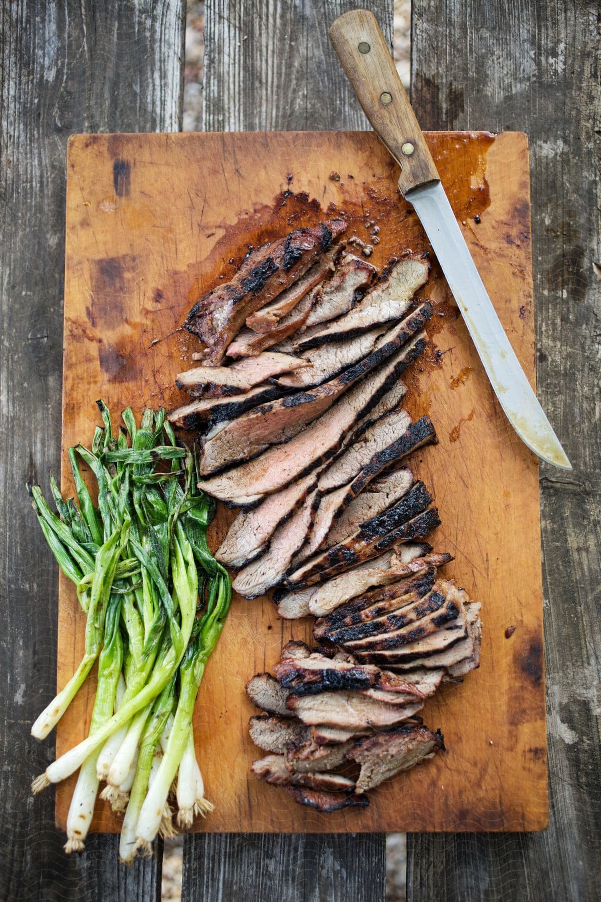 A wooden chopping board with a knife and raw pork