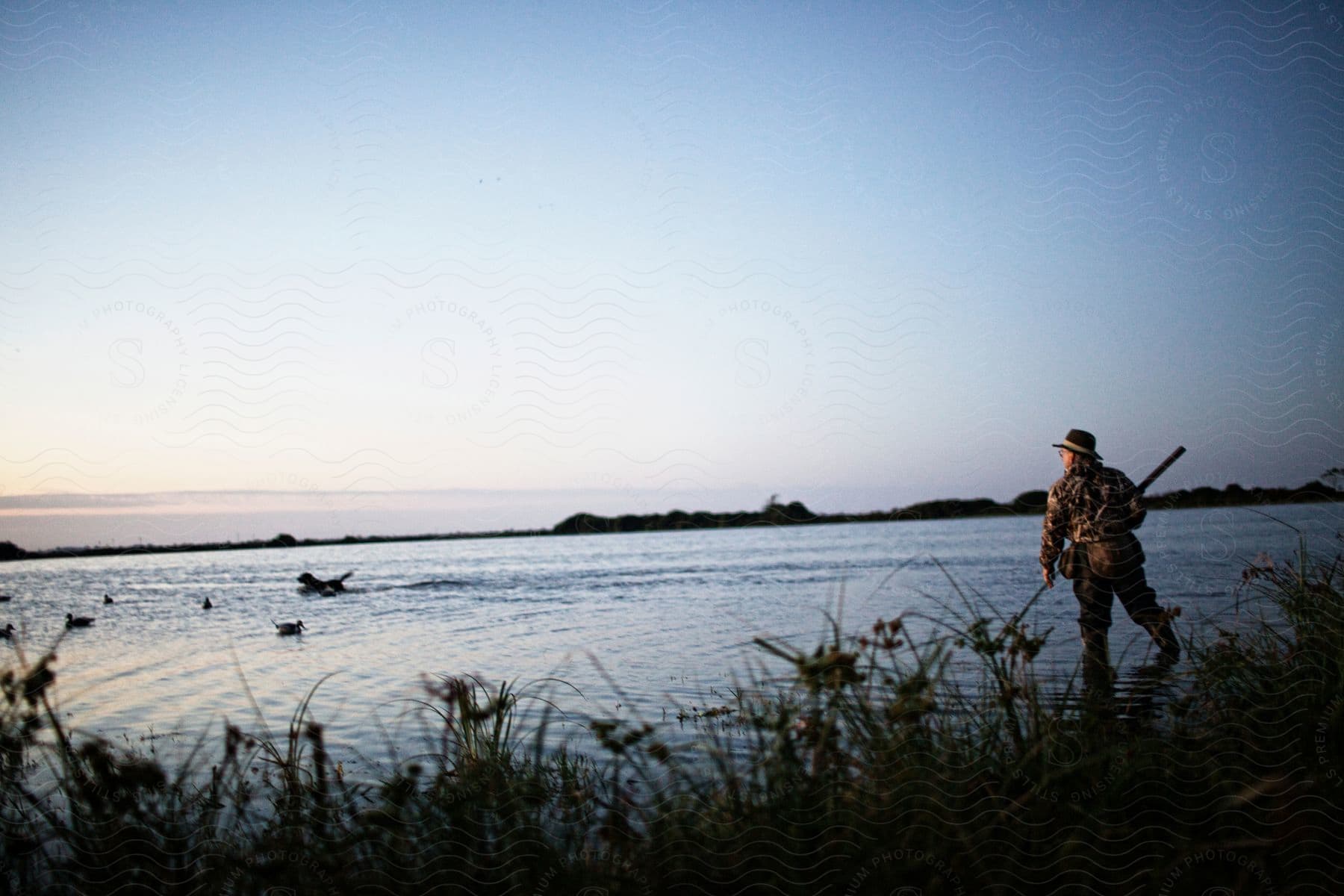 A man in nature near a lake with a bird flying overhead