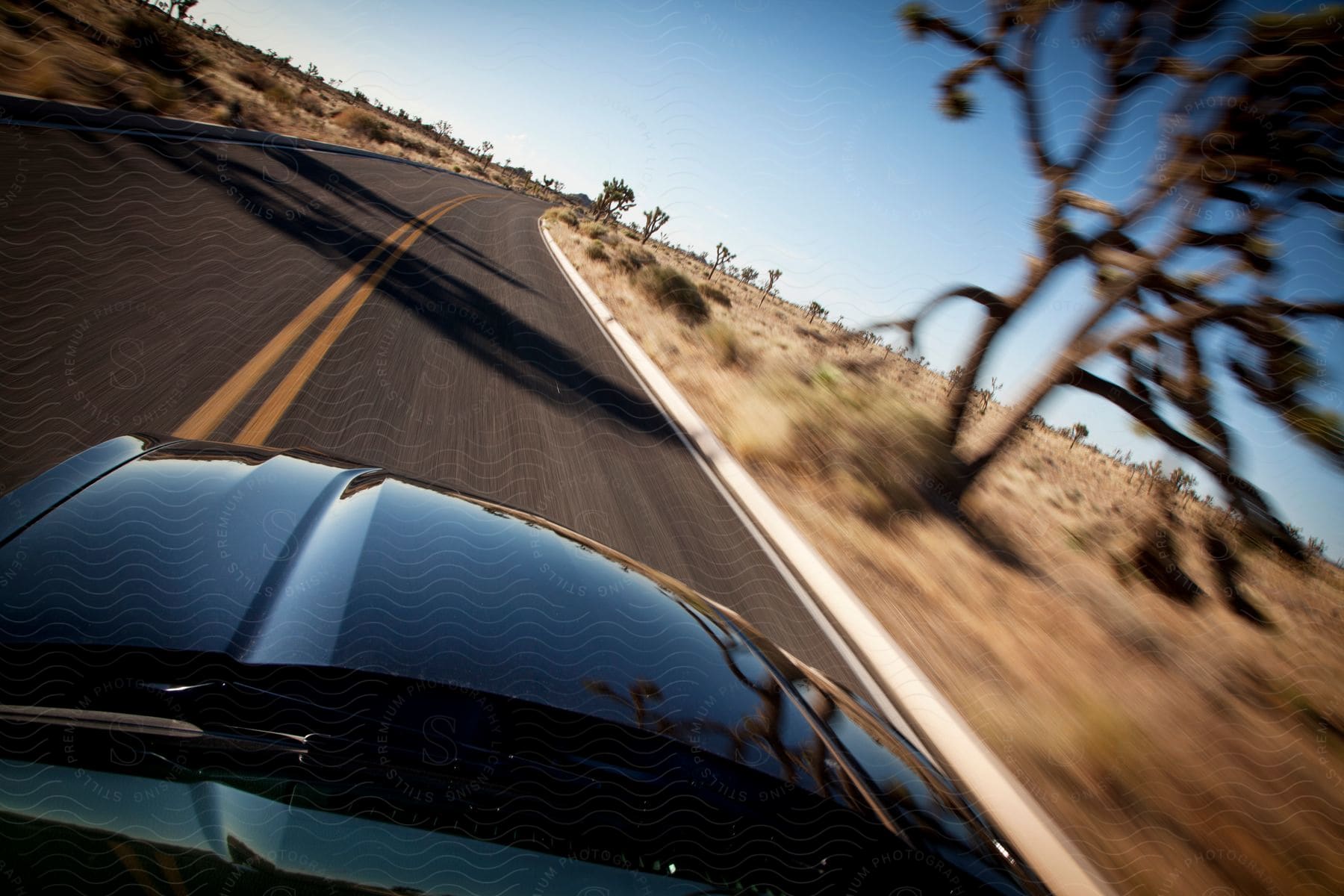 A black car drives on a highway in the desert