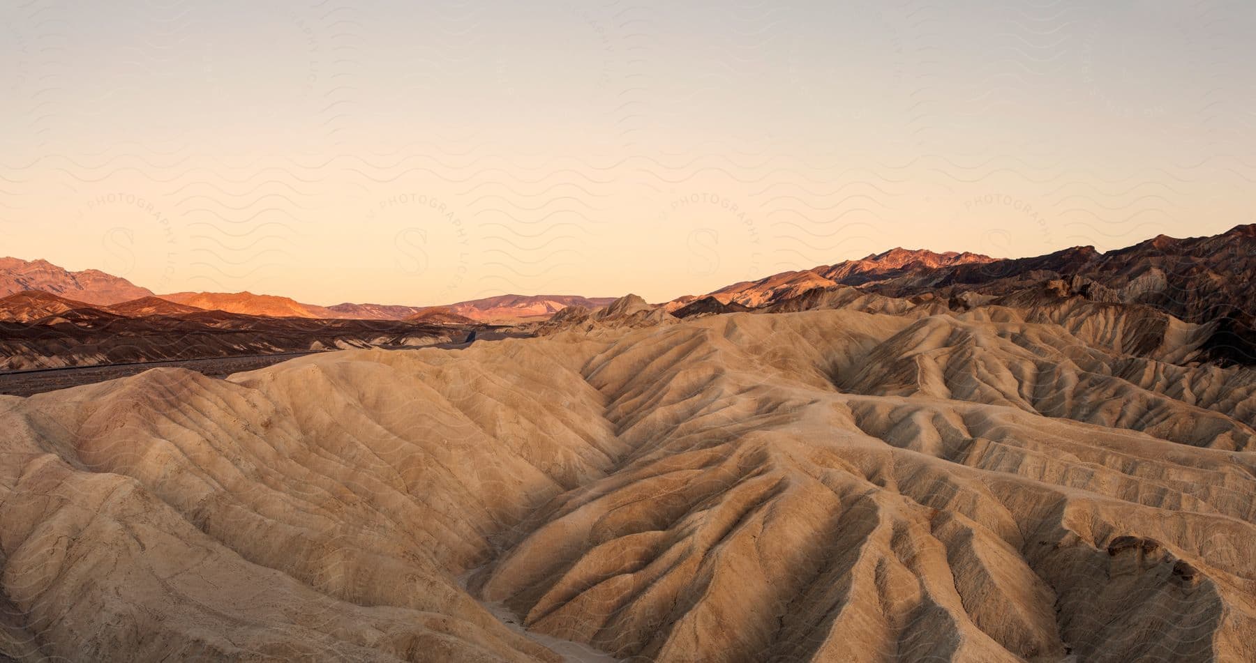 Red desert sand stretches across rugged terrain with hills in the background