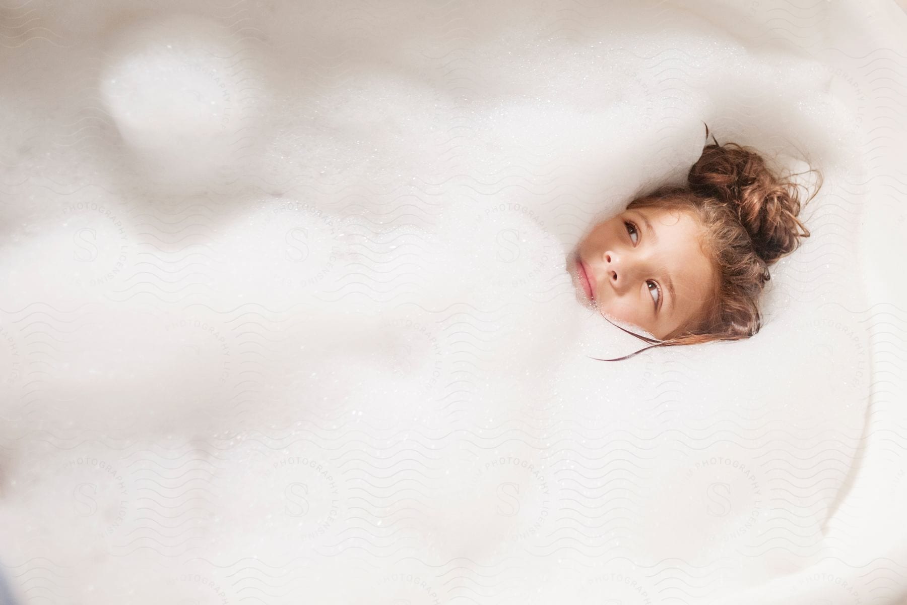 A childs head is visible in a foaming bath