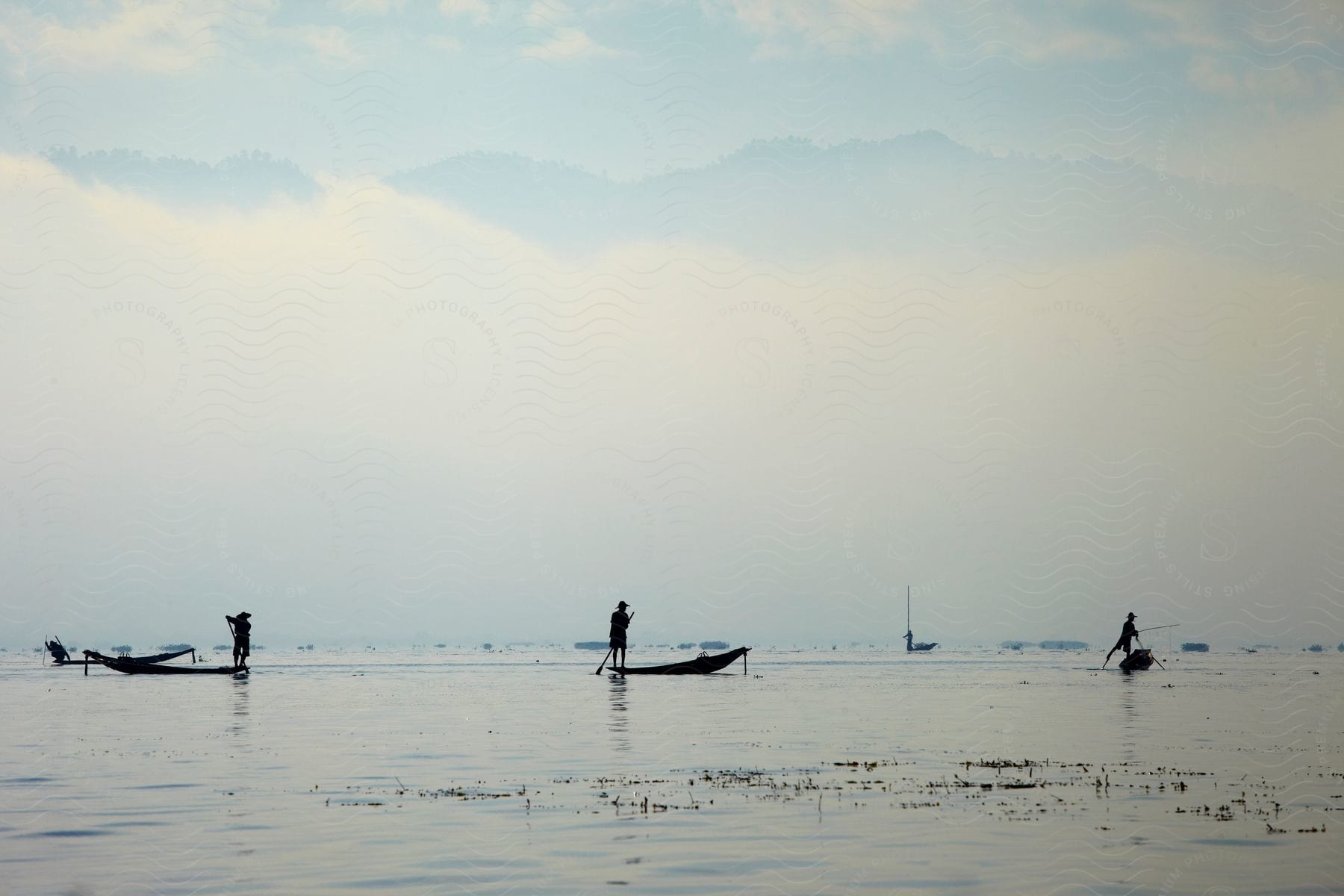 People standing on canoes in the lake