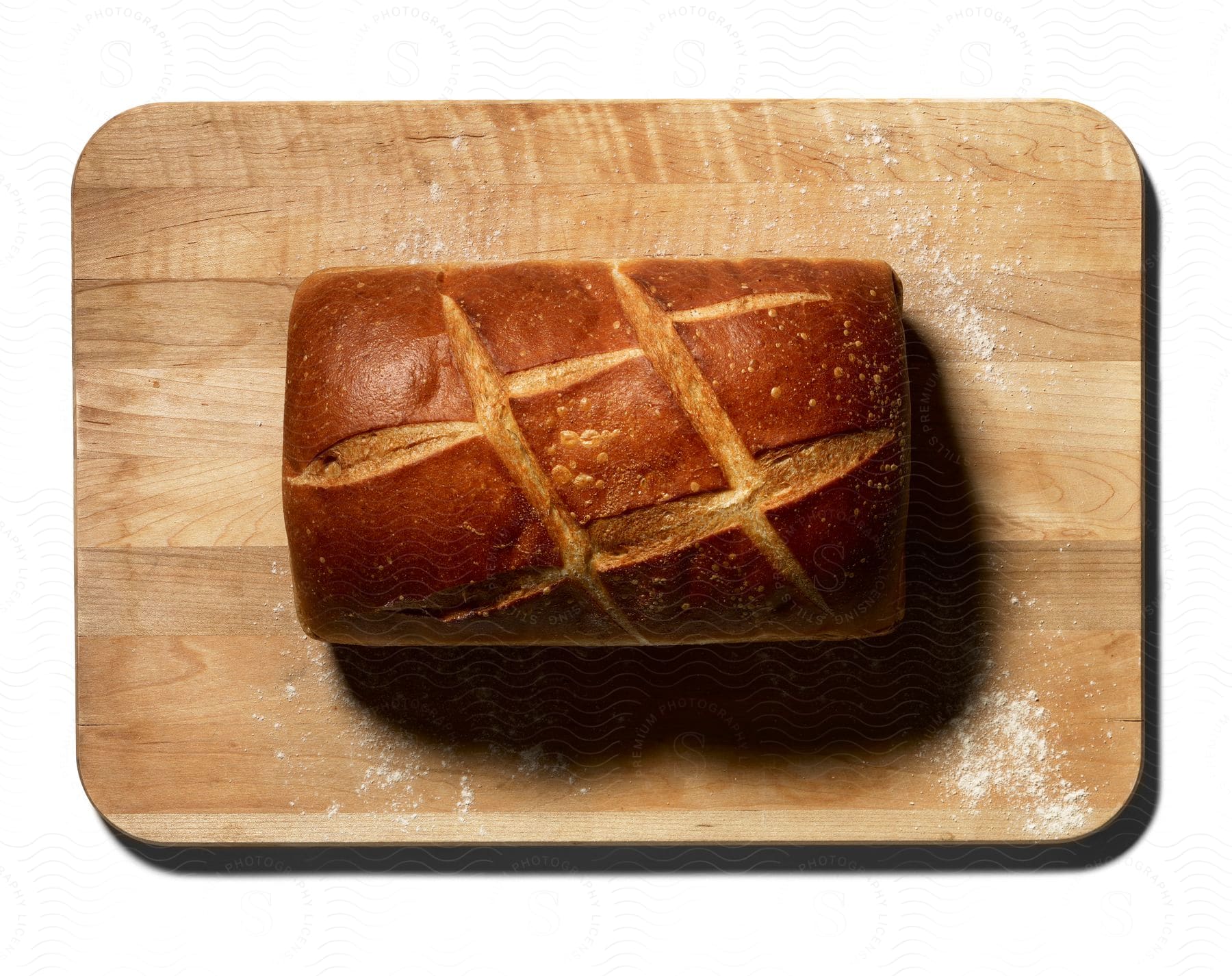 A loaf of bread with cuts sprinkled with flour on a wooden cutting board