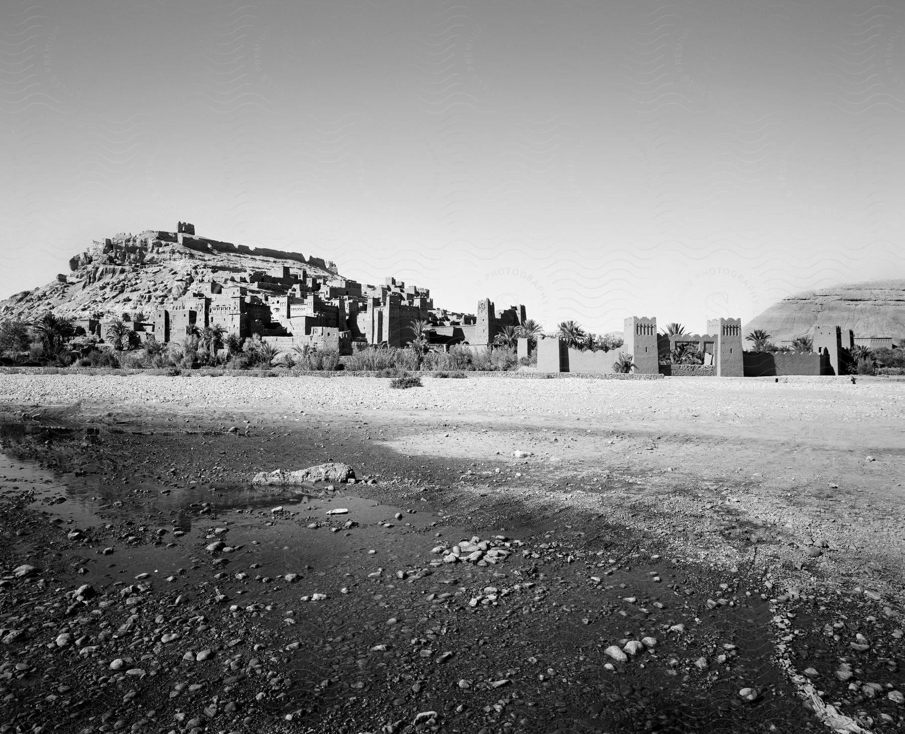 Stock photo of an ancient city in the desert with buildings and a castlelike fortress captured in black and white