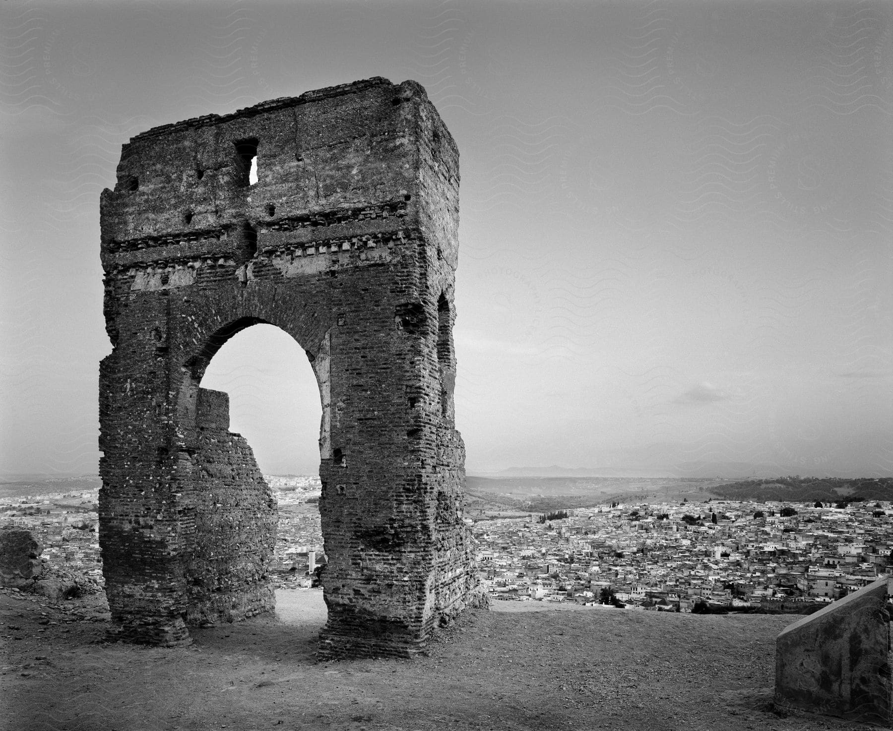 Ancient ruins of a large building with a small coastal city in the background in the daytime