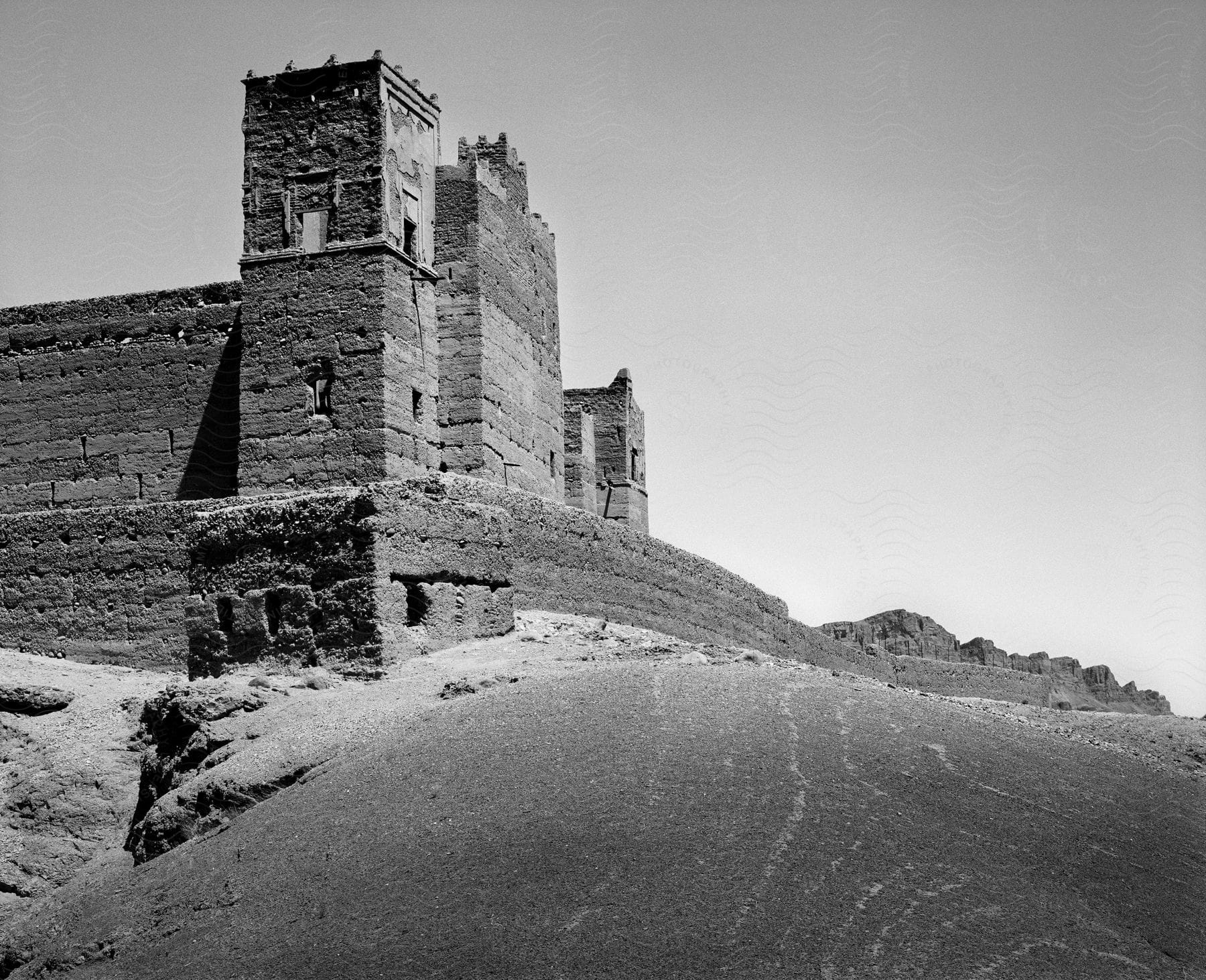 An ancient castle is seen on a hilltop with rocks and sand surrounding it