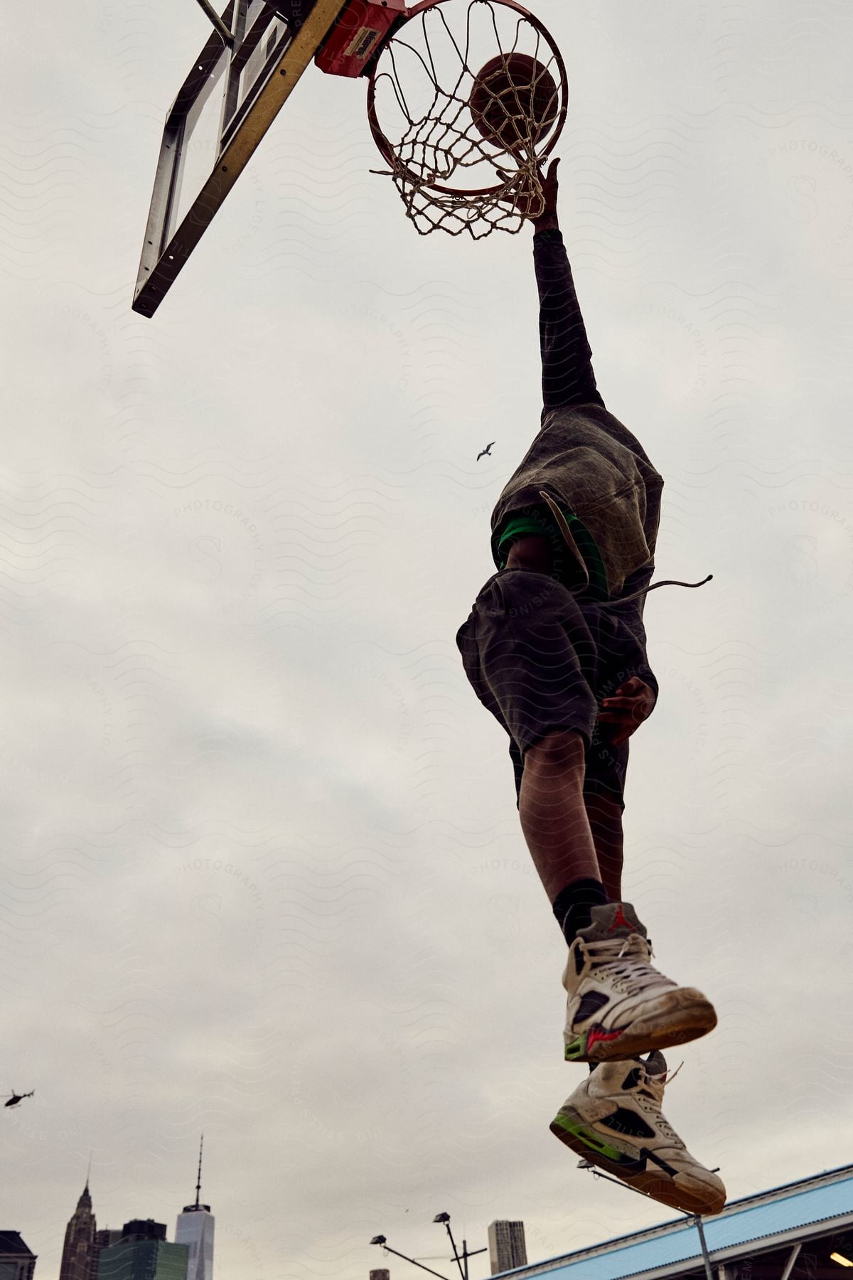 A man is performing a basketball dunk outdoors during the day
