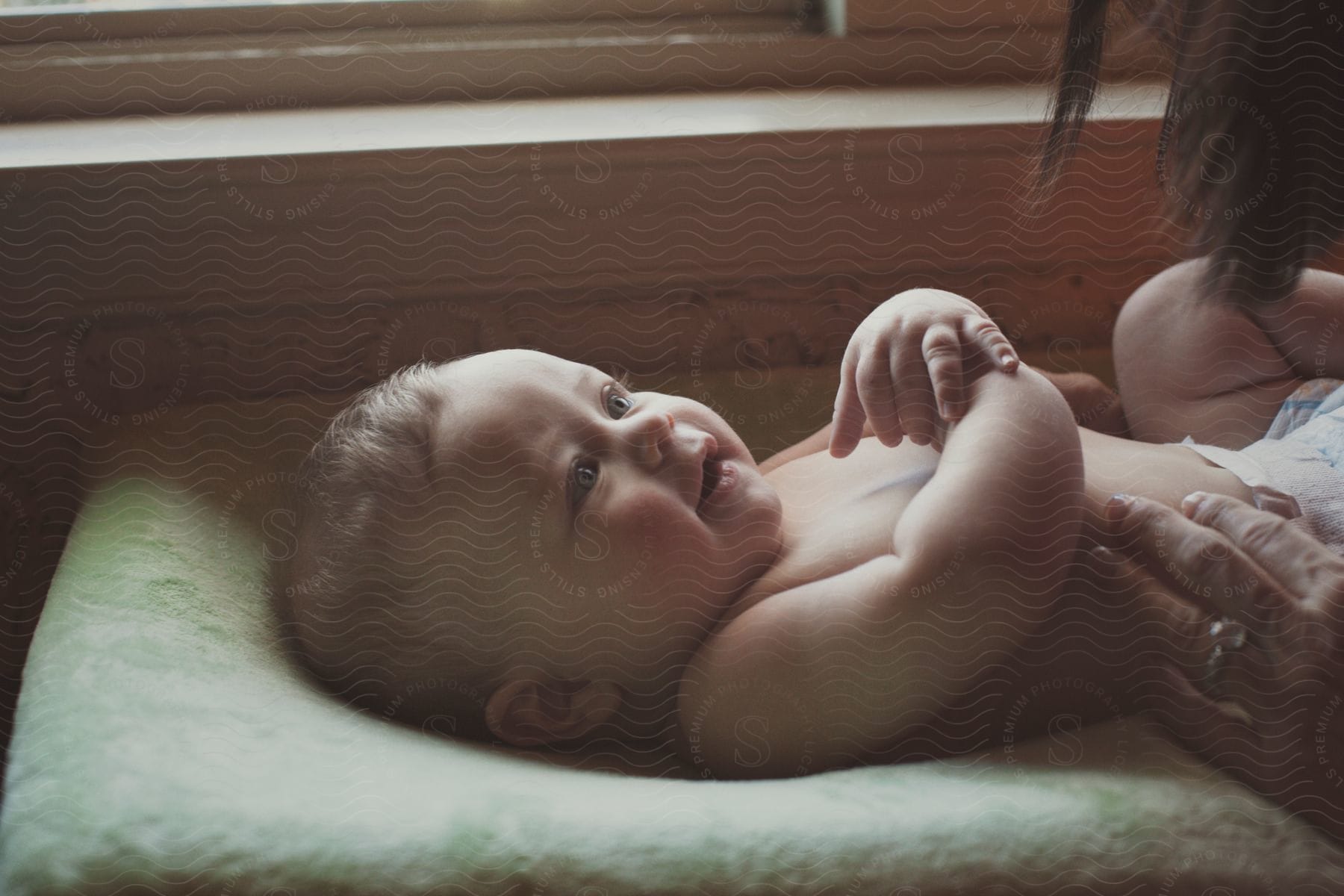 A baby on a changing table with a woman patting his belly