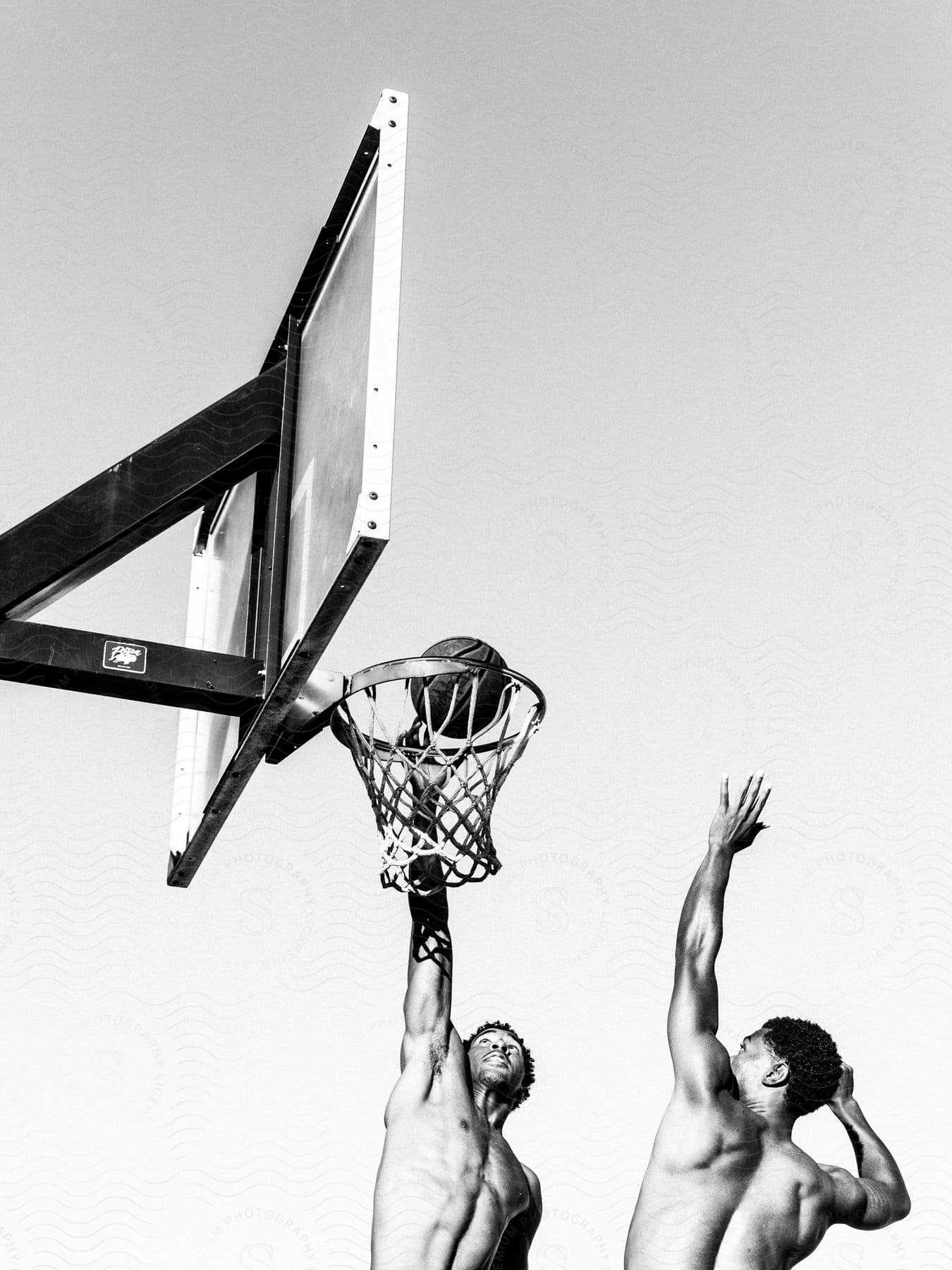 Two men playing basketball without shirts