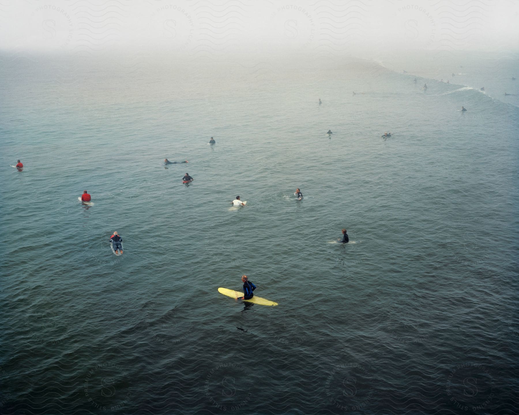 A group of people on surfboards waiting for a wave in the ocean