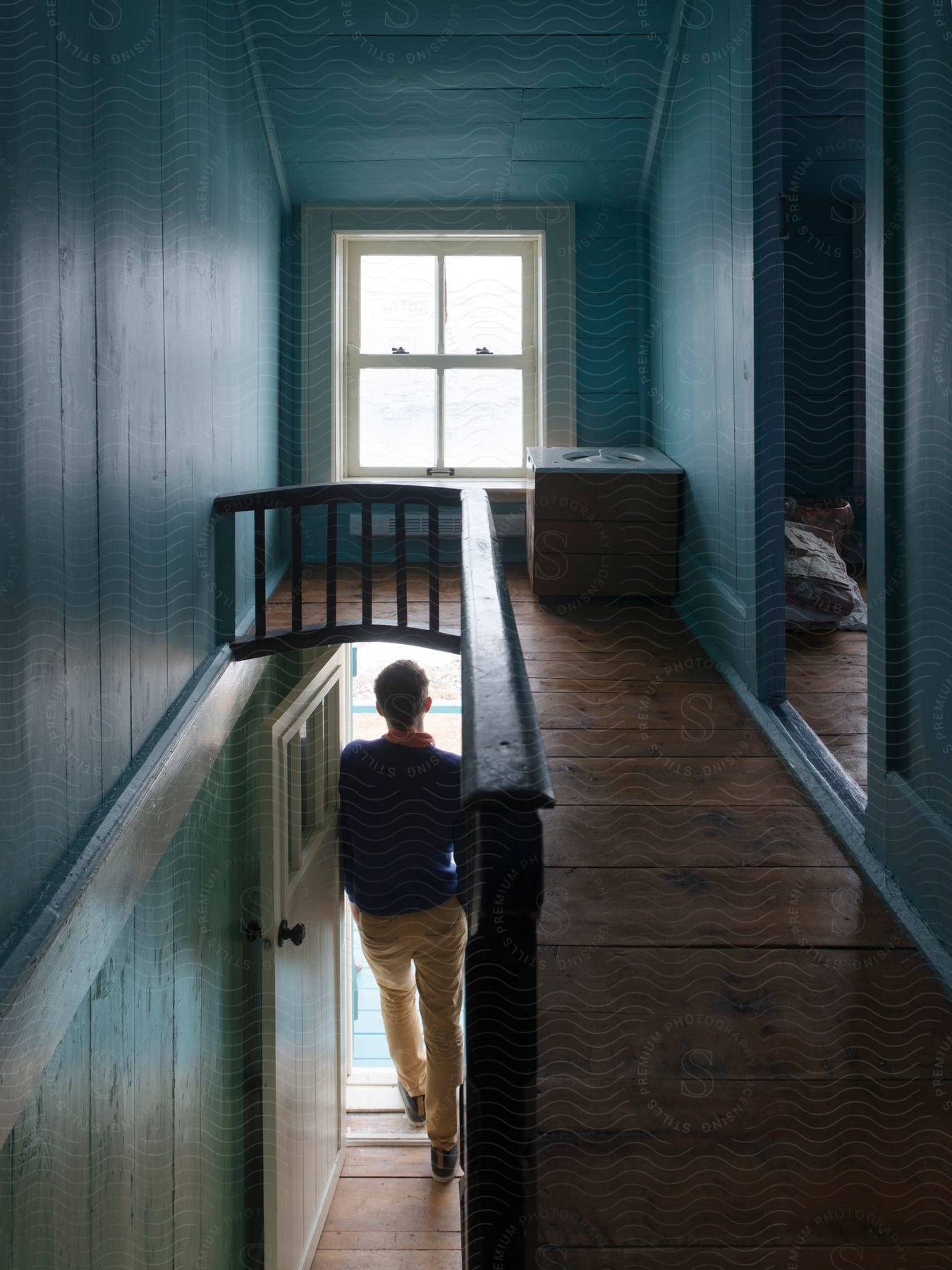 A man stands at a doorway looking out from a very narrow home