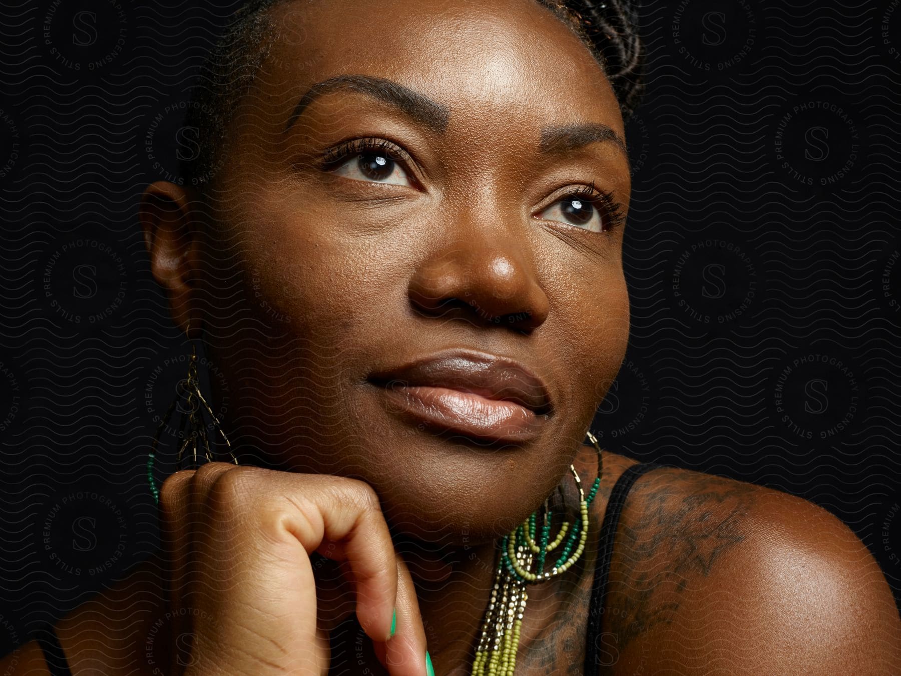 A black woman poses indoors resting her hand against her chin