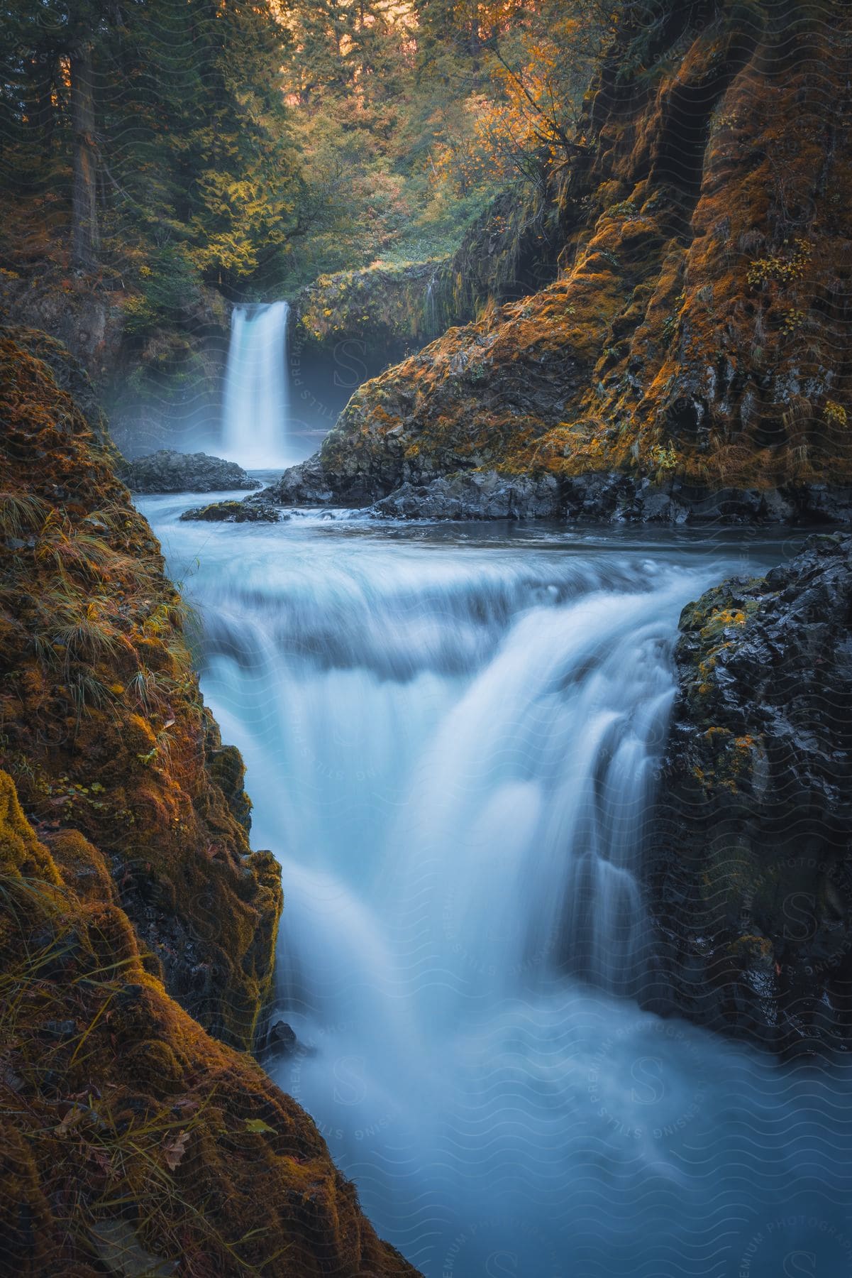 A waterfall flows between large rocks in the fall