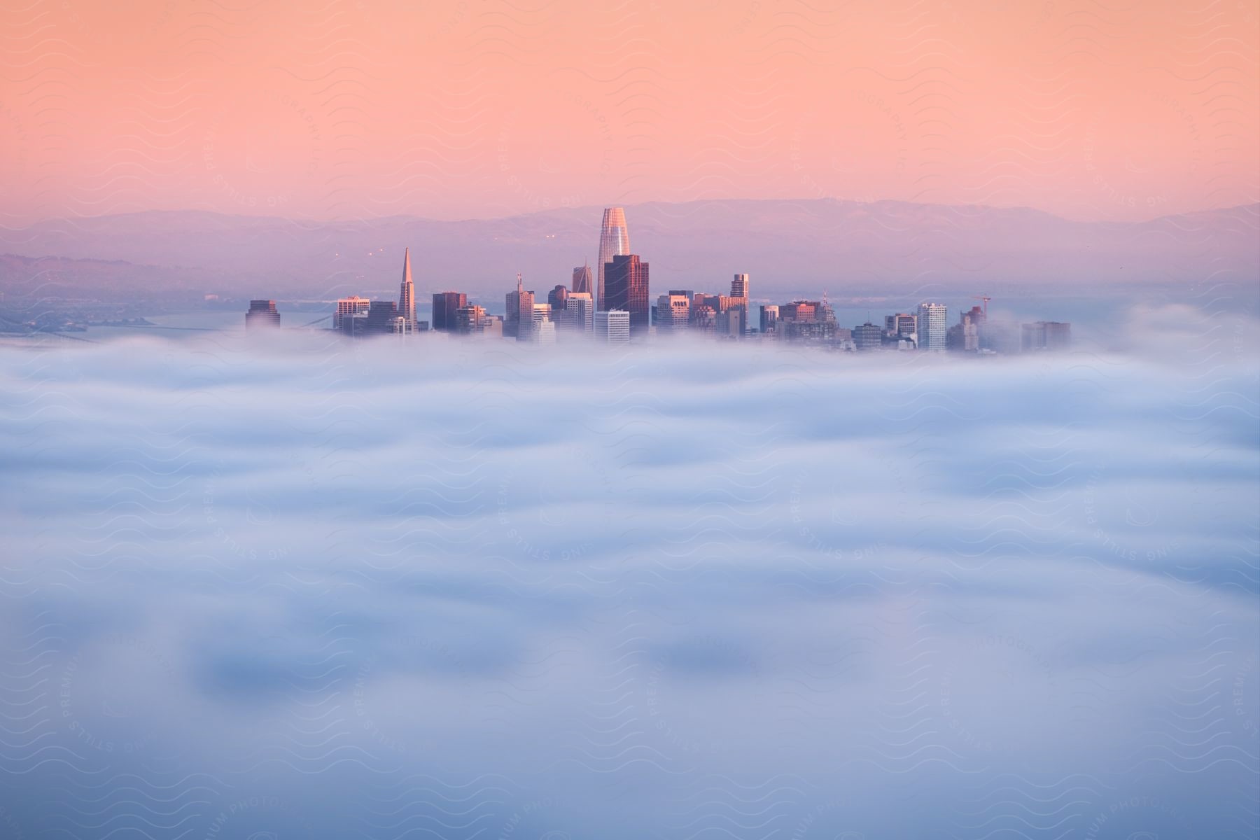 Aerial shot of fog over a city at sunset with a pink sky