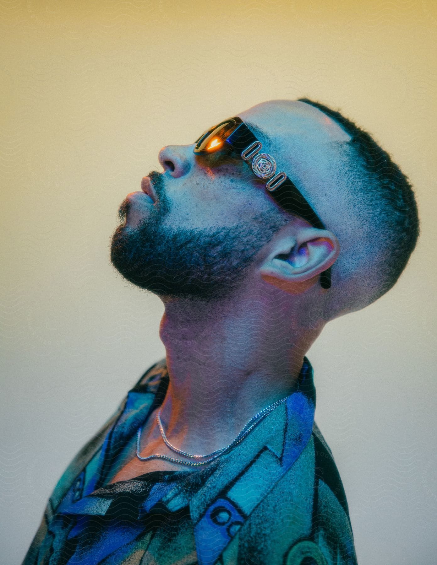 A person with a beard is seen in profile wearing versace sunglasses