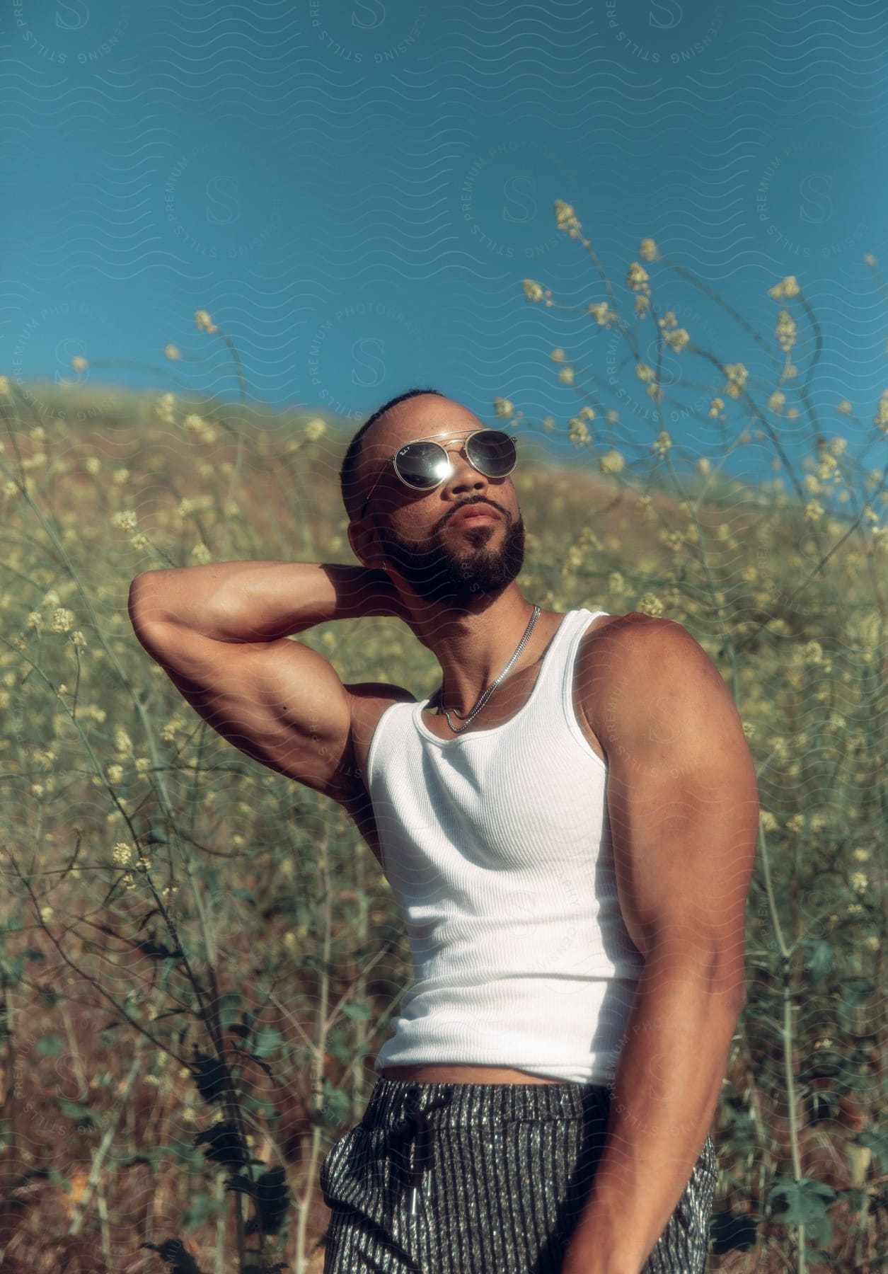 A man wearing sunglasses and a necklace posing in the woods