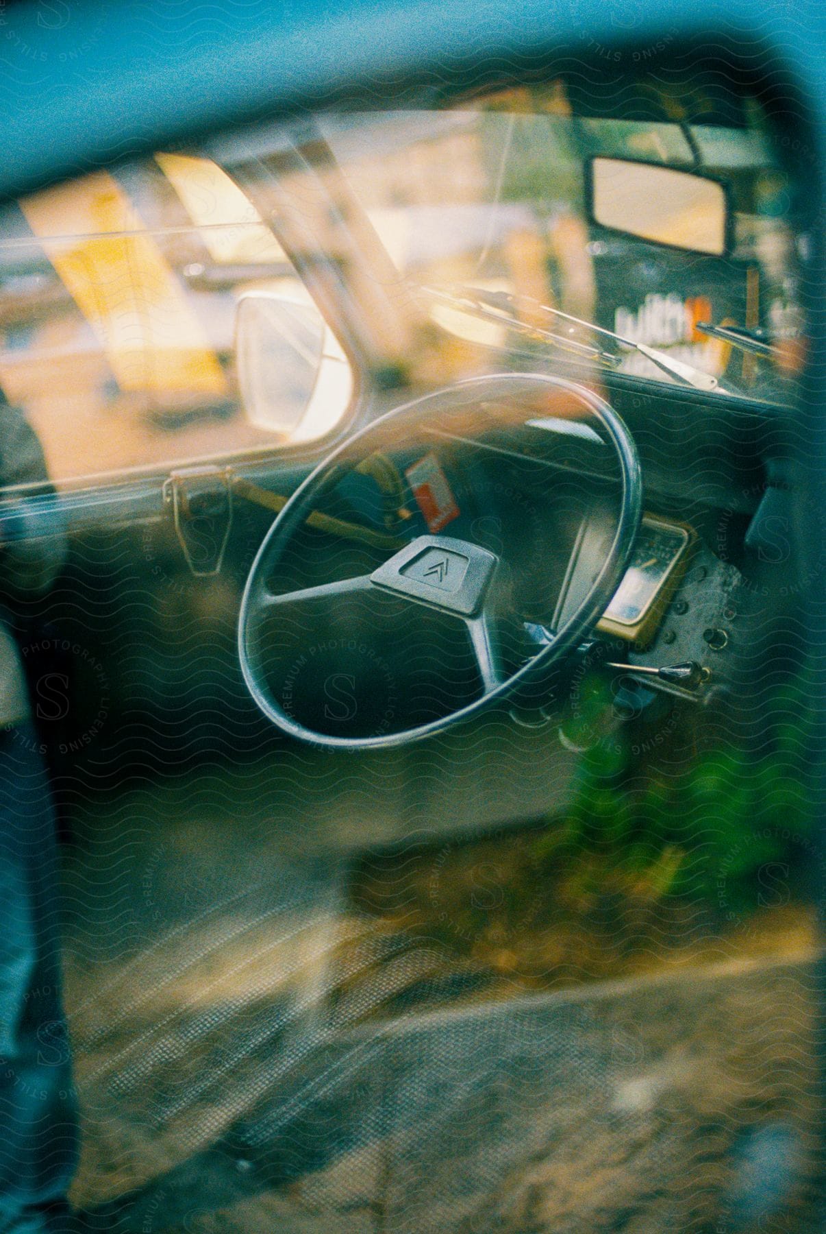 In a city with shops in the background the interior of a truck is shown including the steering wheel and seats