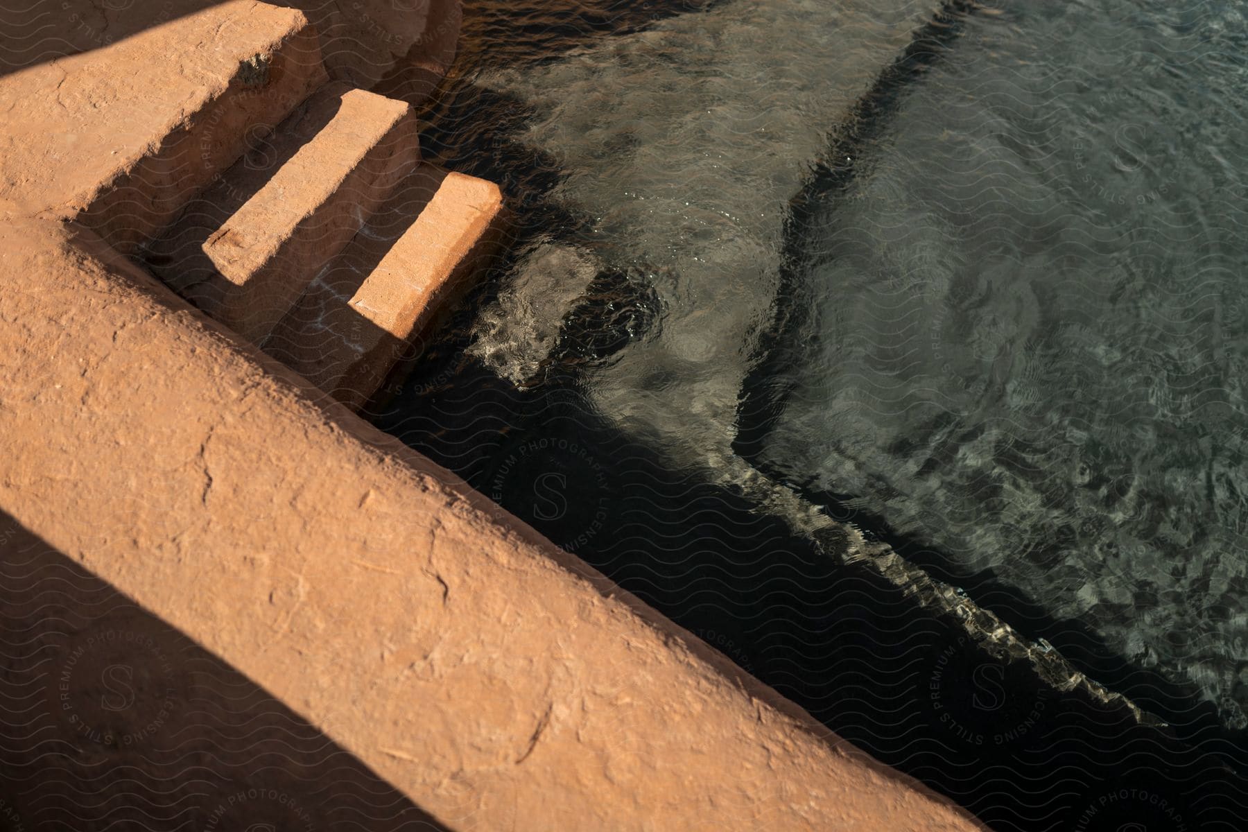 Sandcolored concrete stairs leading to a swimming pool