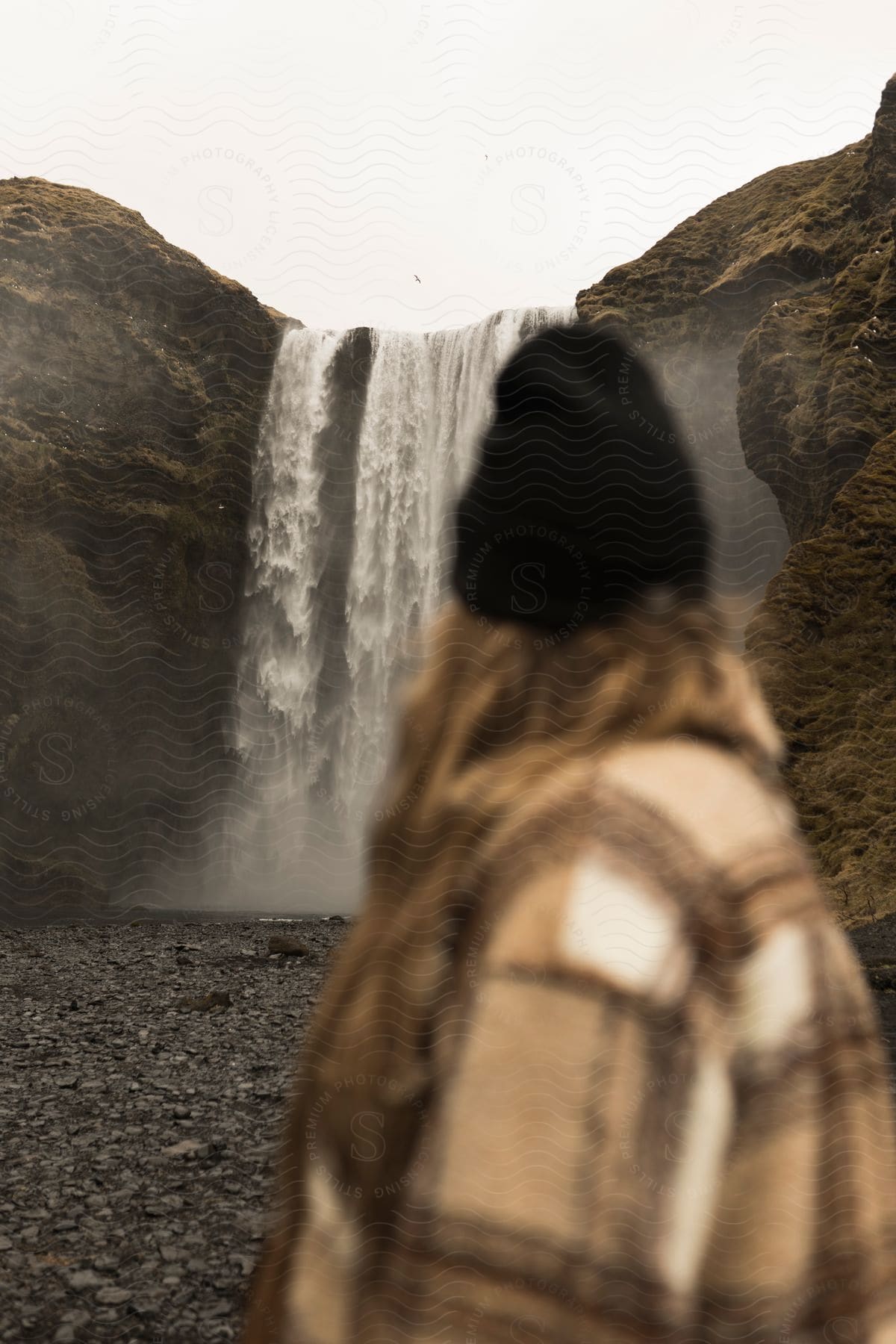 A woman observes a waterfall in a rocky landscape