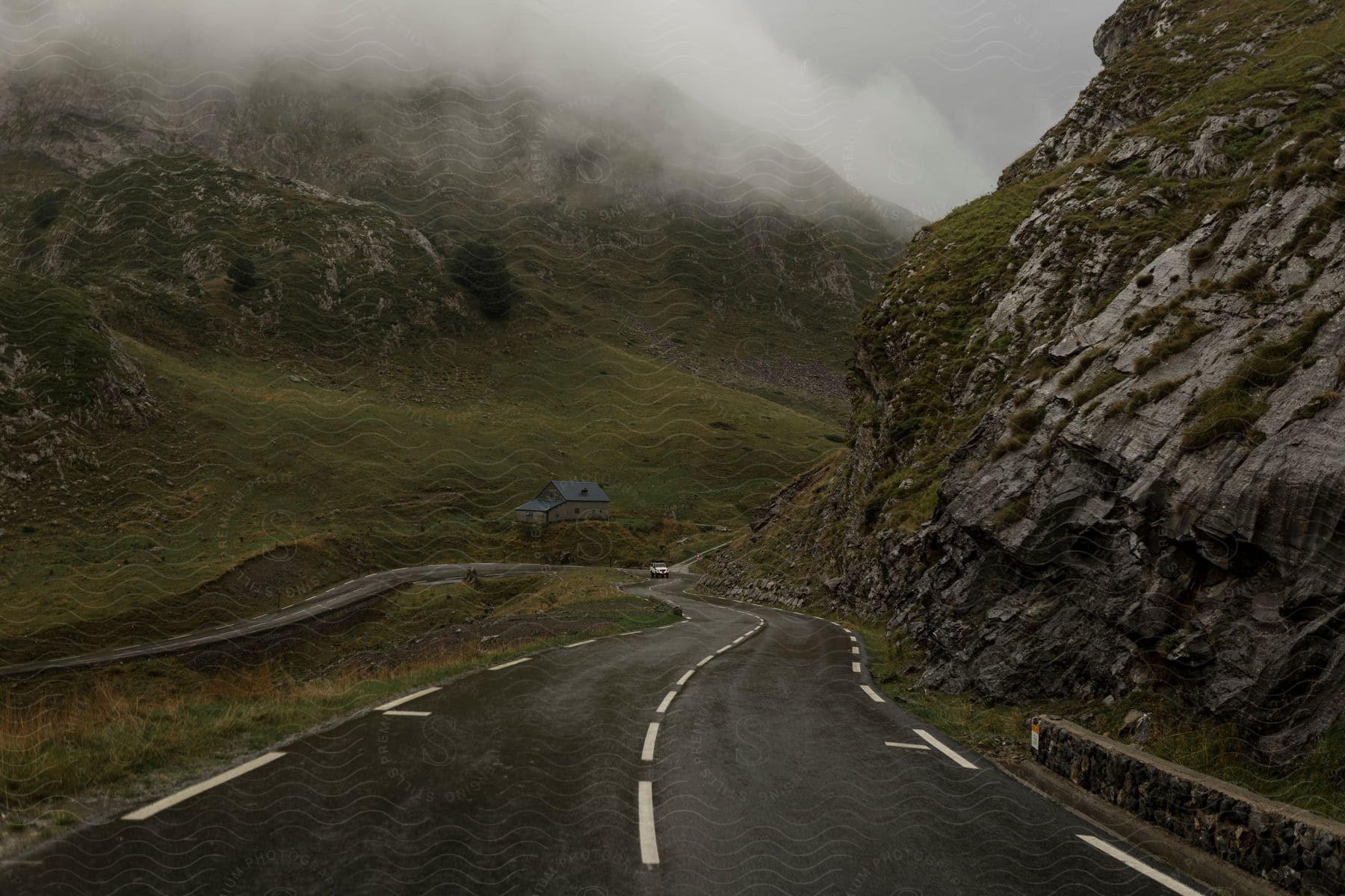 A car approaches the camera on a highway in the mountains