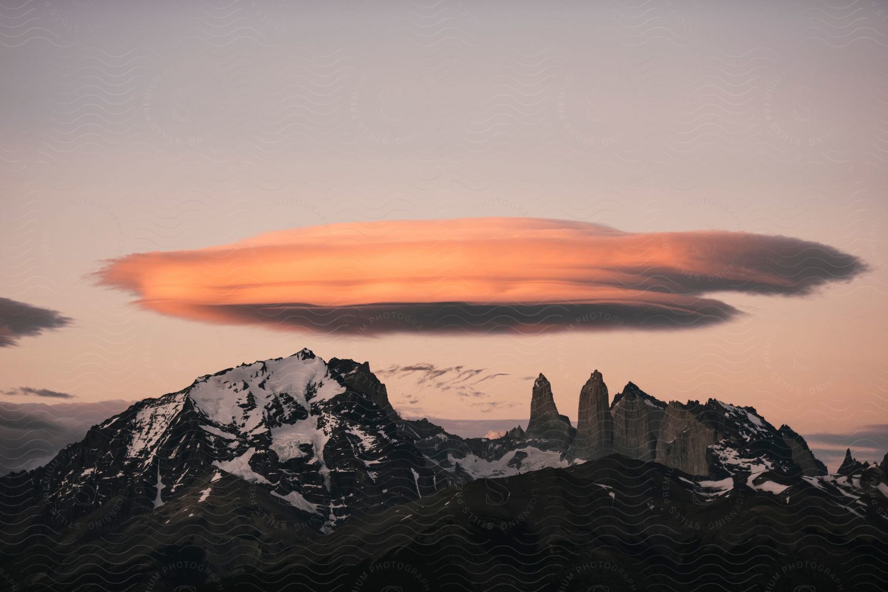 A serene mountain landscape at sunrise with snowcovered peaks and clouds in the sky