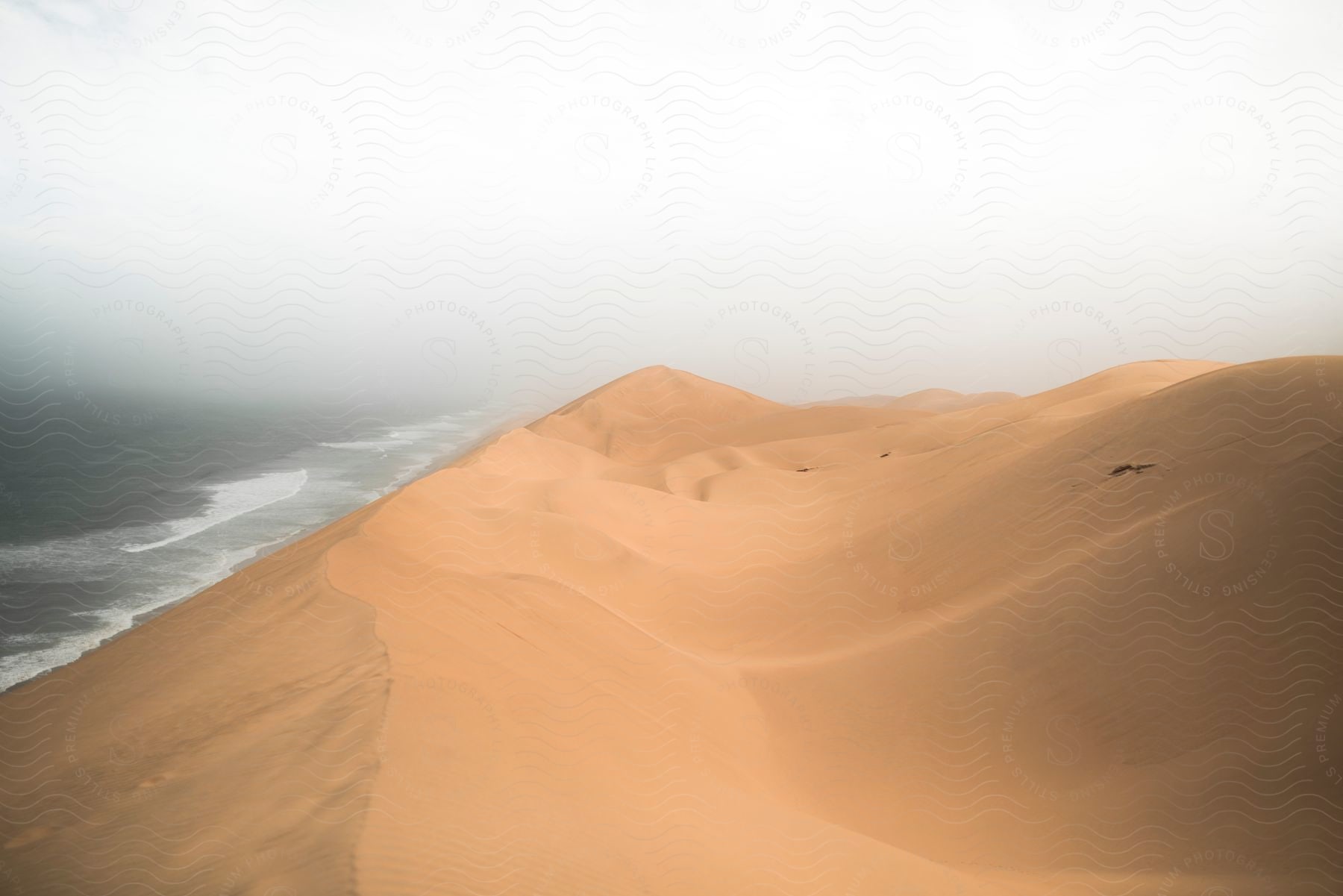 Sand dunes next to the ocean on a cloudy day