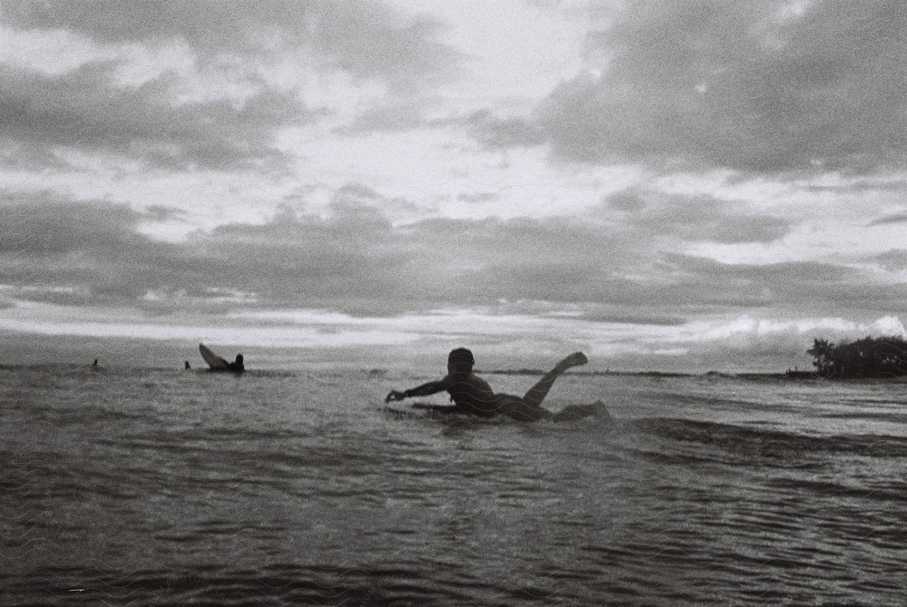 A boy is lying on a surfboard in the ocean