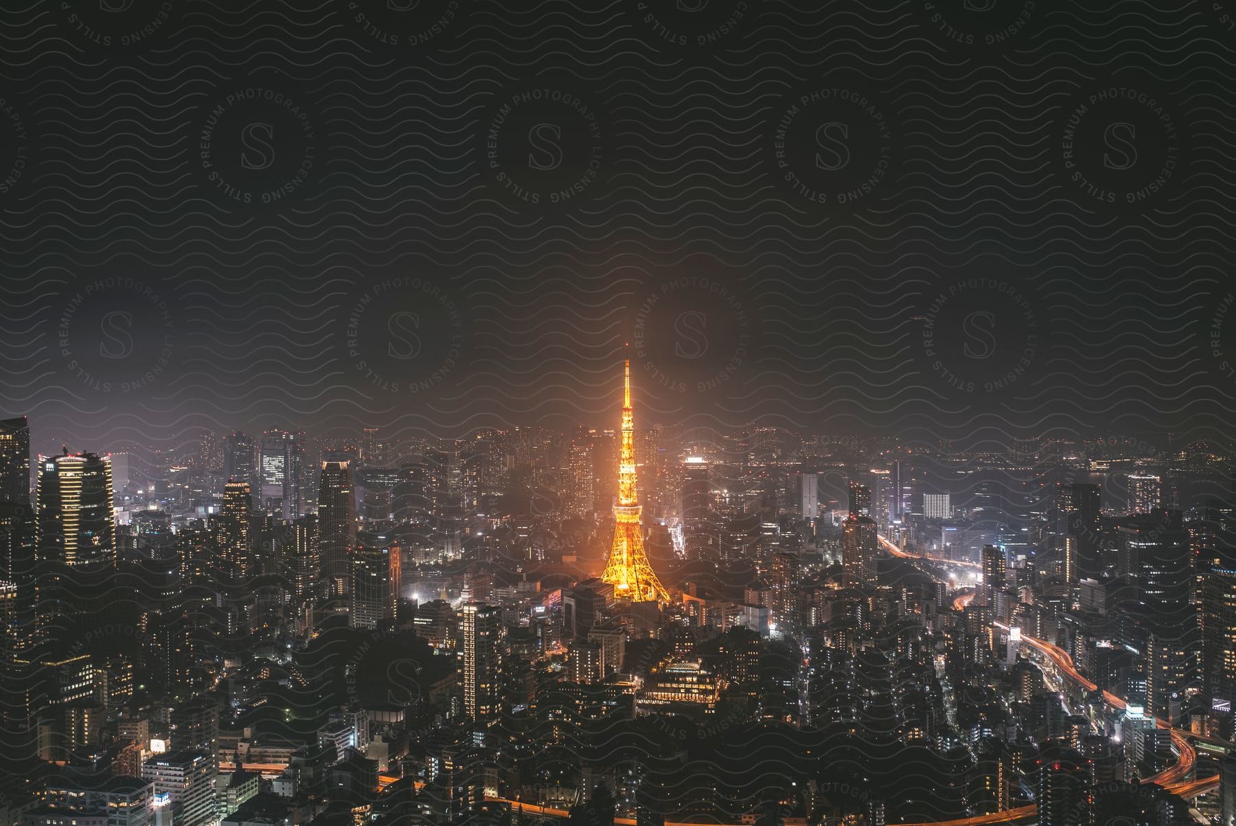 Tokyo tower is illuminated in yellow dominating the tokyo skyline at night