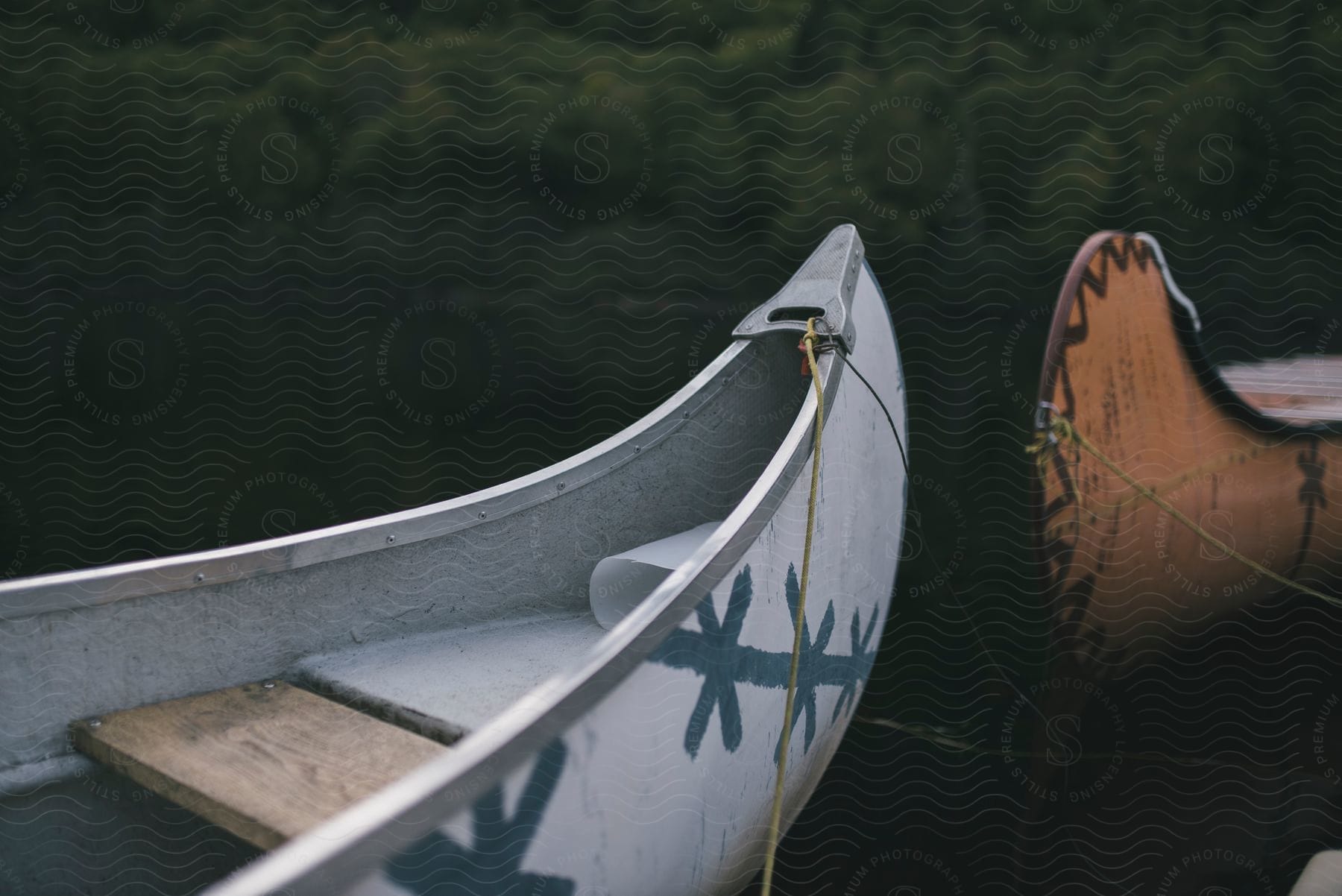 A white and a brown canoe standing over the water with vegetation on the background