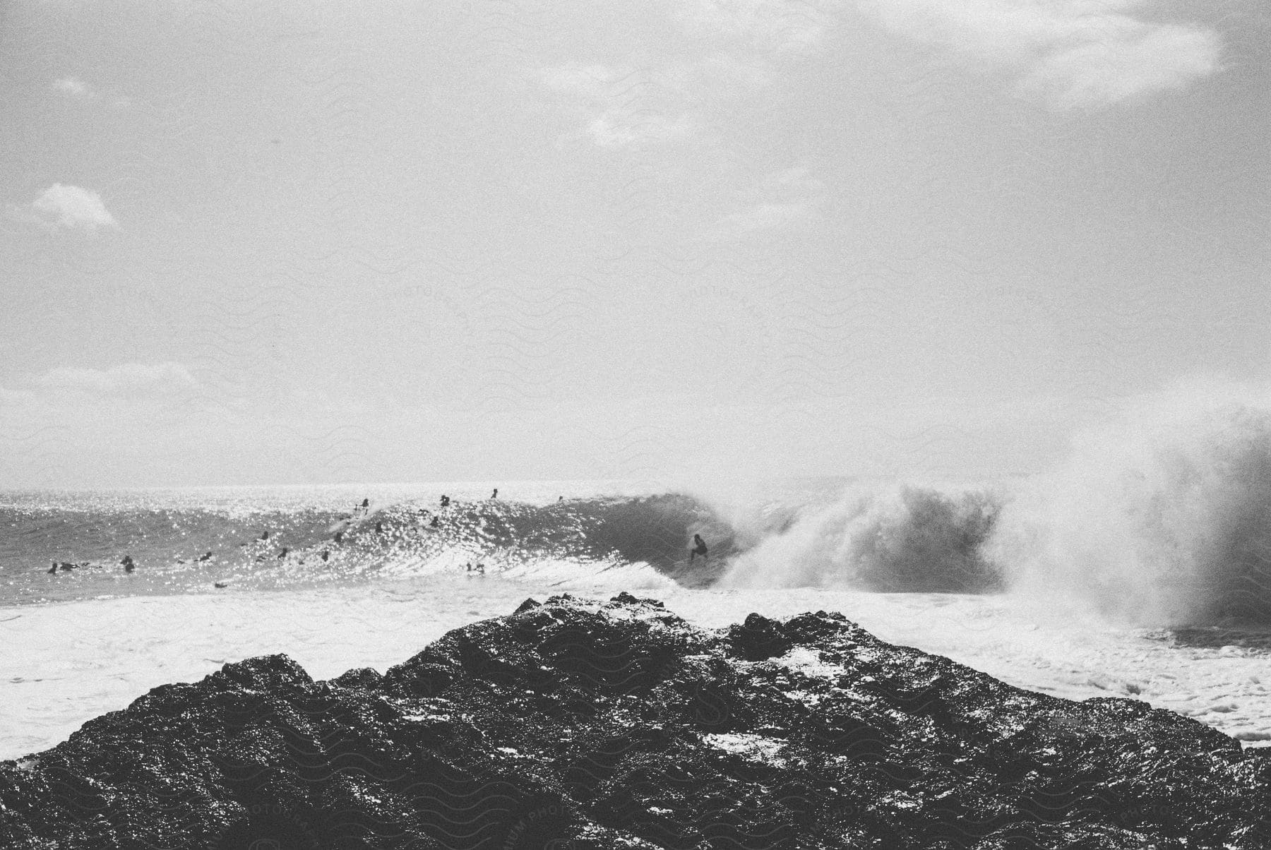 A rocky structure with a sandy beach ocean and a crowd of people in different spots