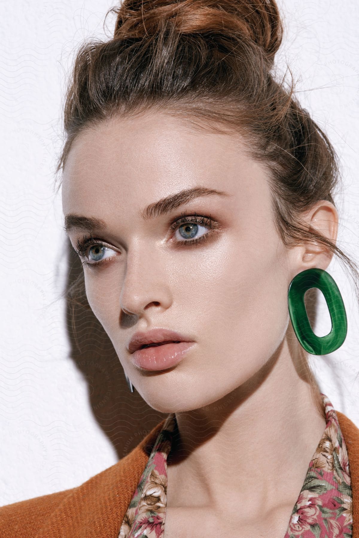 A young woman with her hair in a bun looks to the side