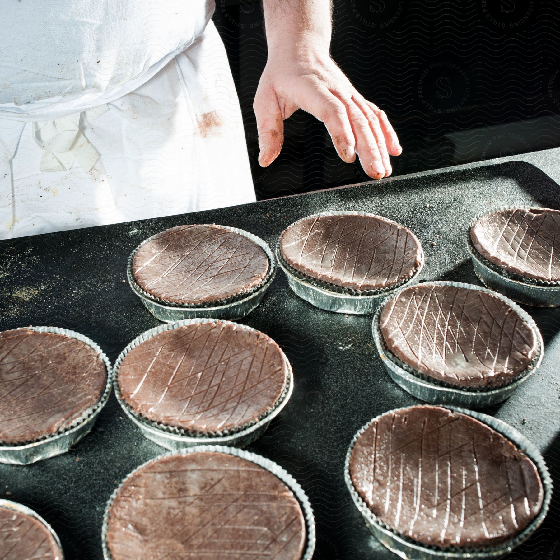 Stock photo of a chef prepares multiple chocolate pies on a large baking sheet