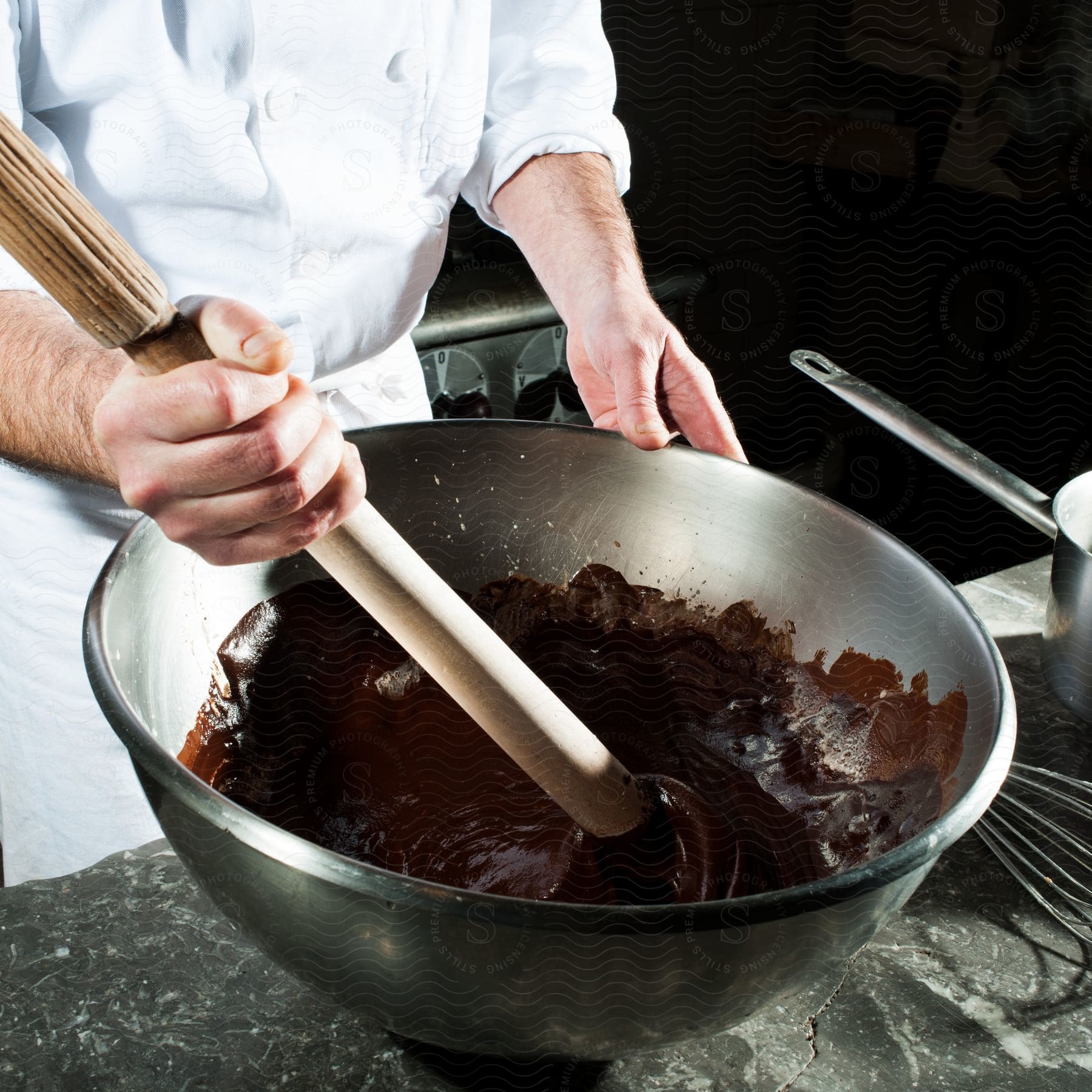 A person mixes ingredients in a bowl using a wooden utensil