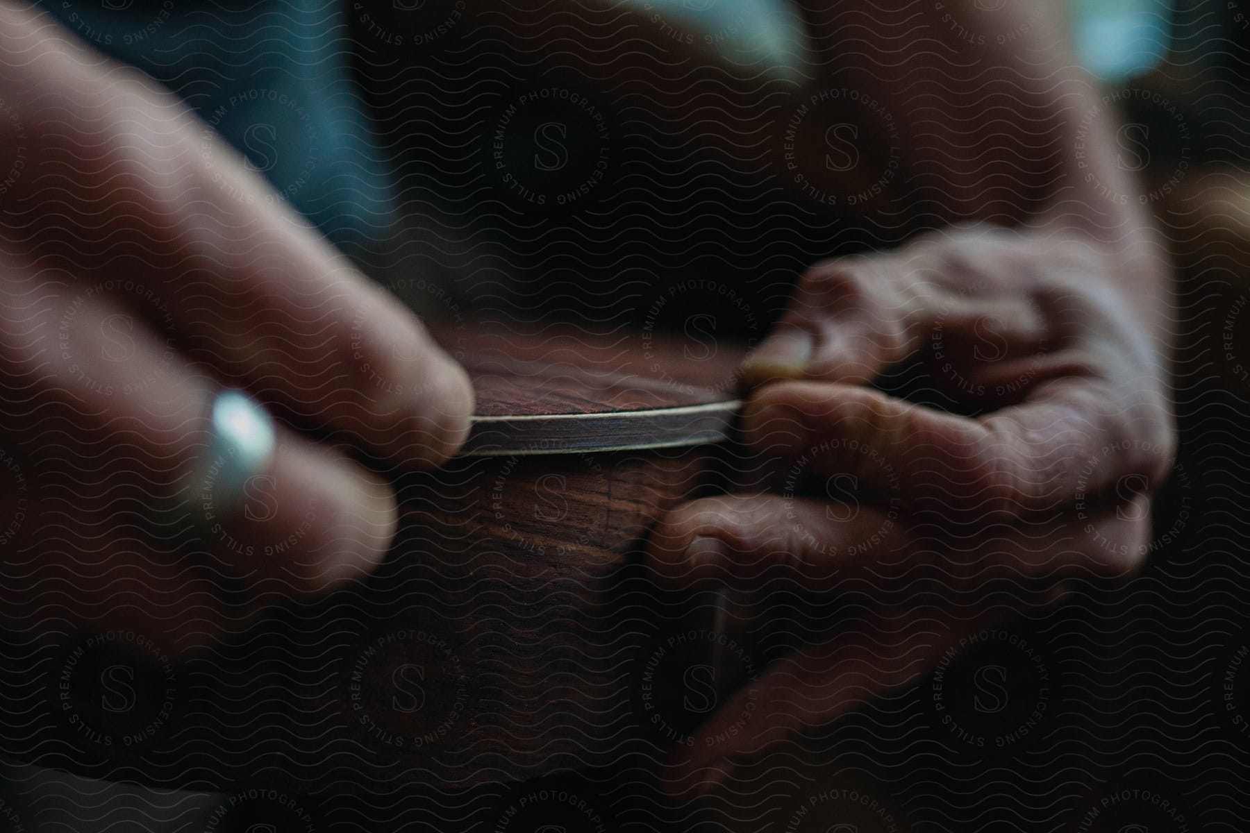 Craftsperson presses metal rim on circular wooden box