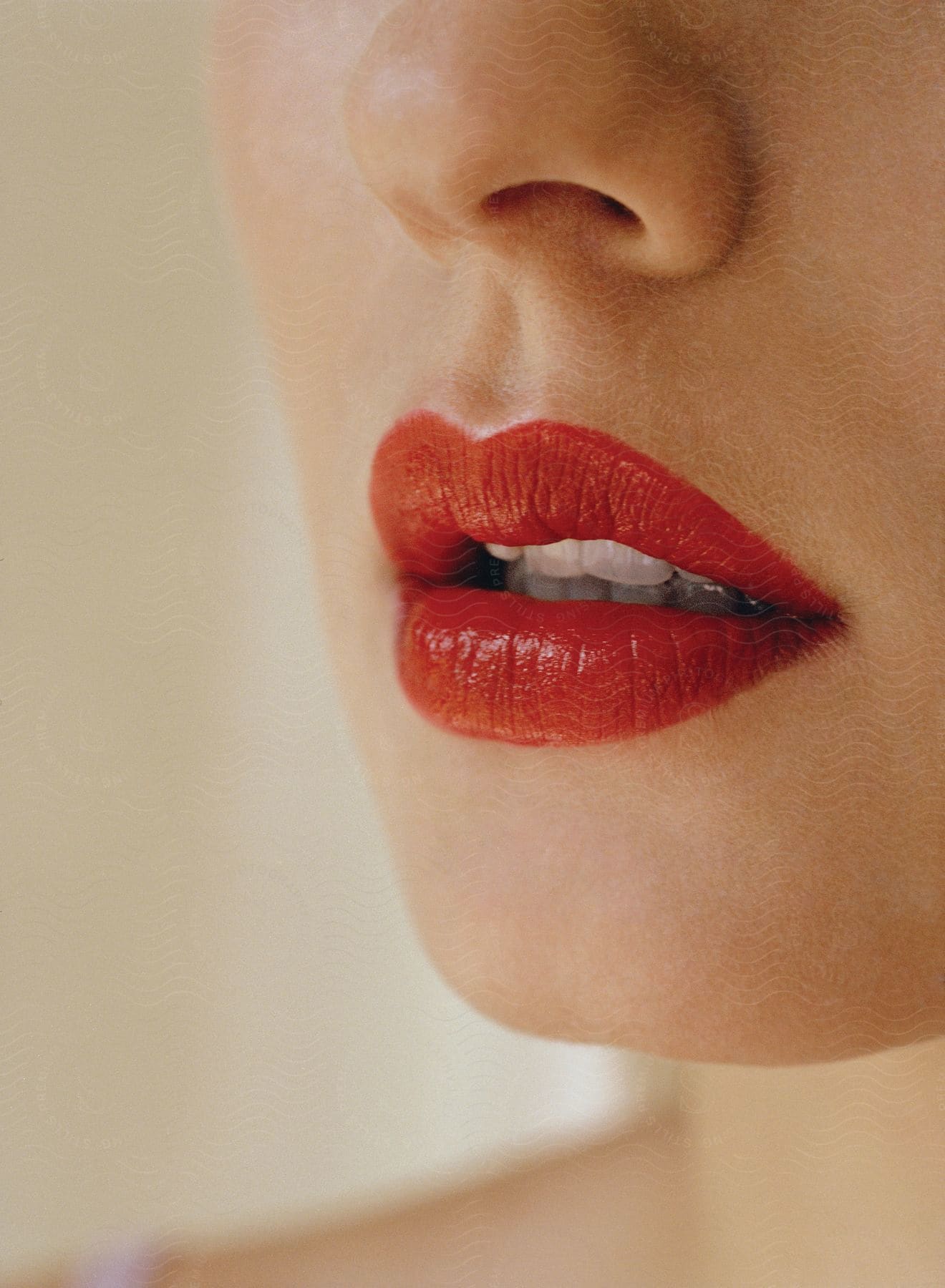 A womans lips with red lipstick showing a slight amount of teeth