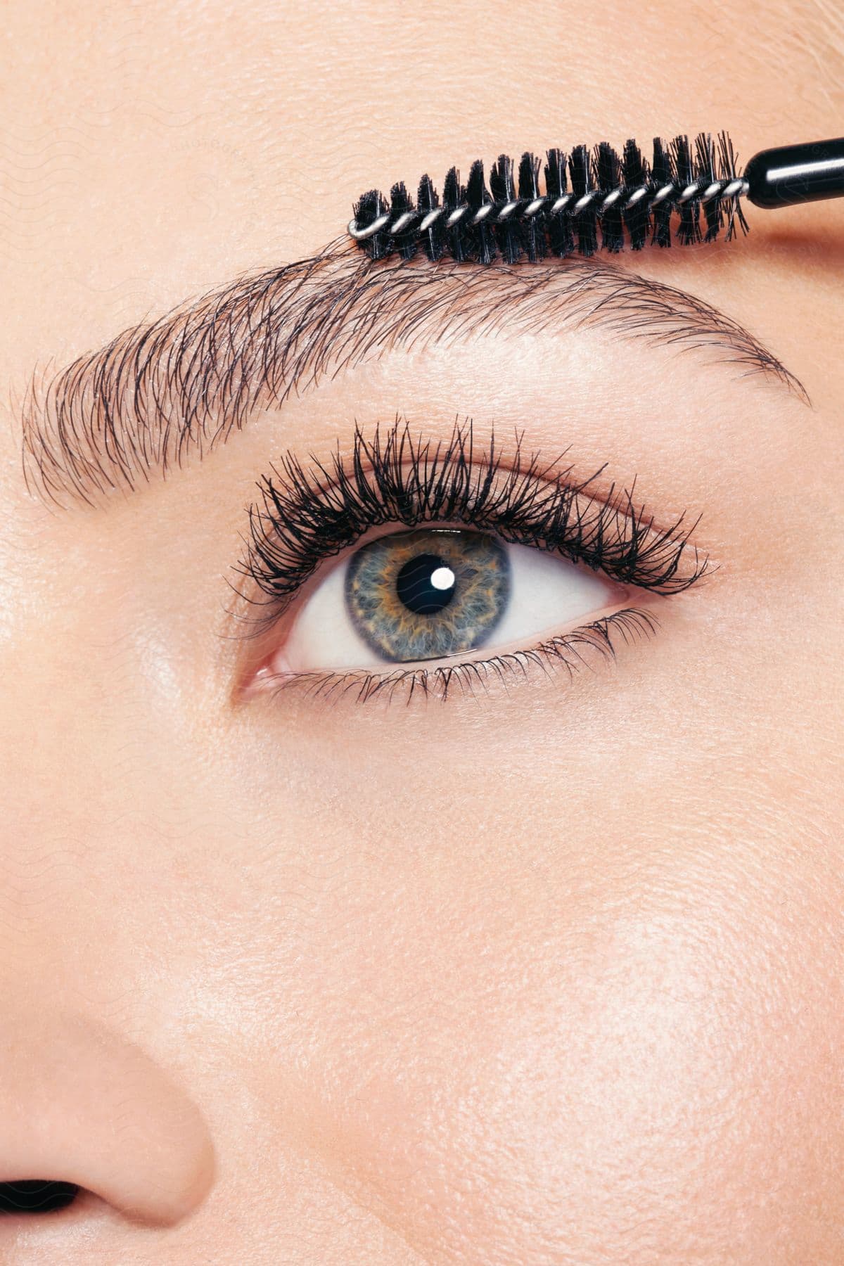 A womans iris is magnified as she applies mascara to her eyelashes revealing the fine hairs