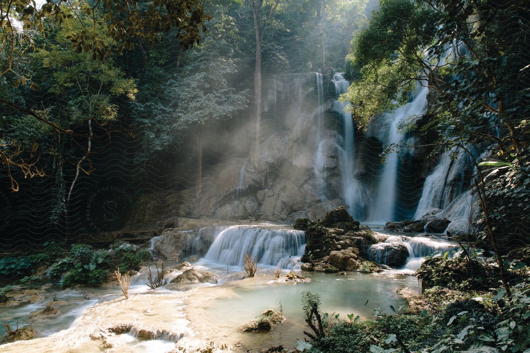 Light streams on a grotto at the bottom of a cascade of waterfalls