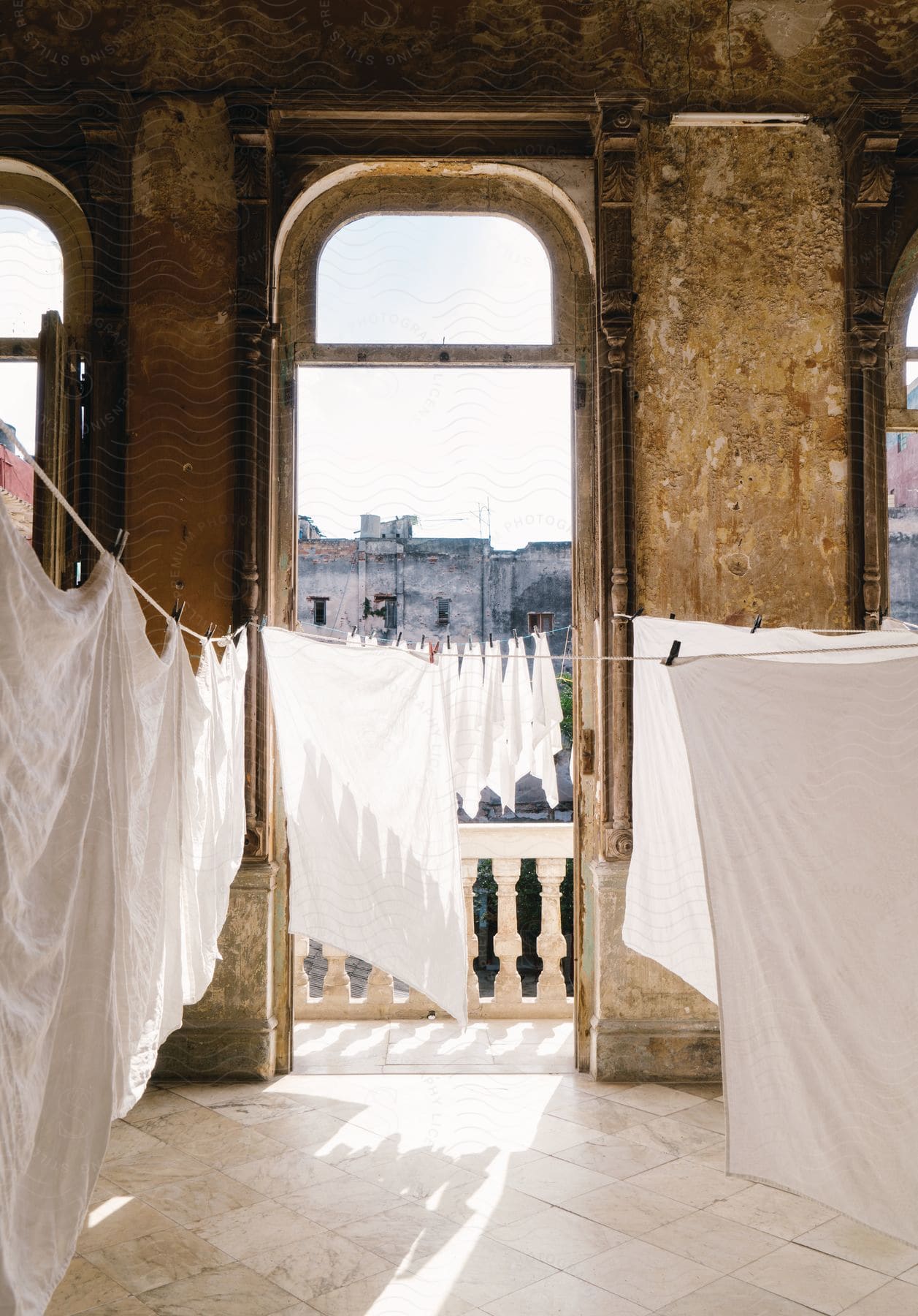 White clothes hanged to dry both inside an old house and on its balcony