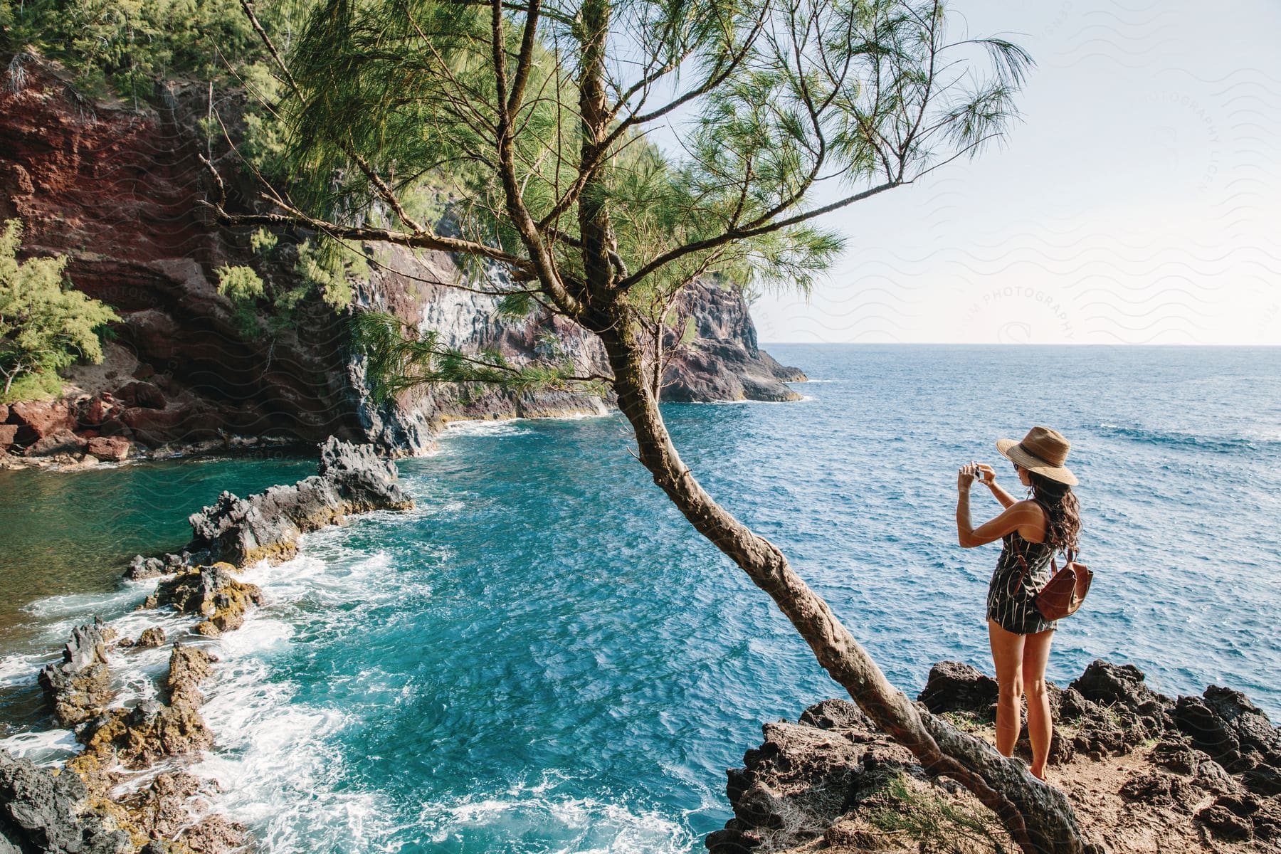 A woman takes a photograph on a rocky shore