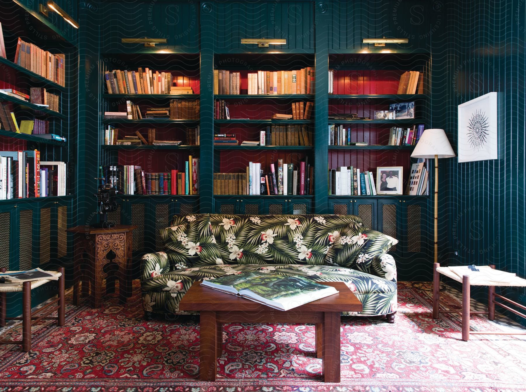 A home library filled with books featuring shelves a couch tables art and reading lamps