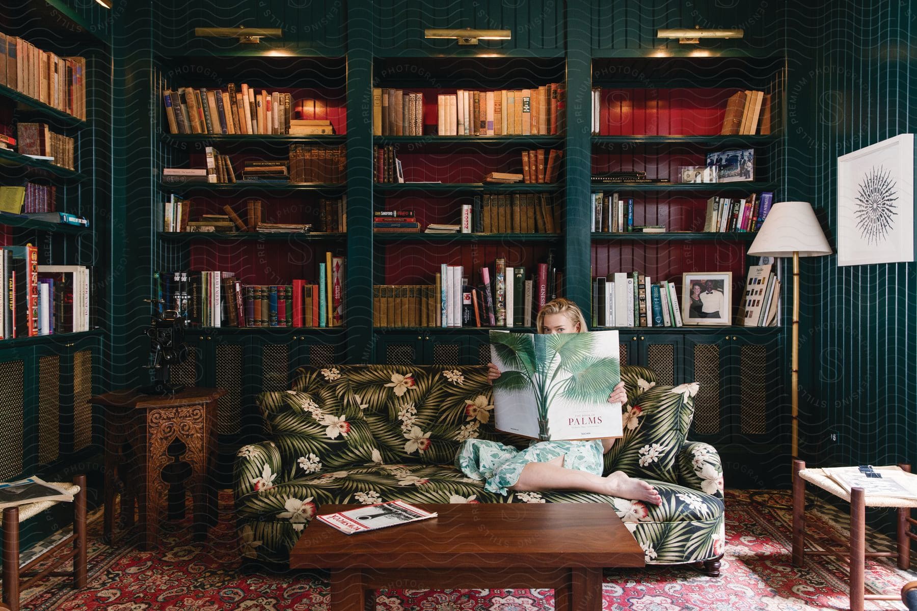 A woman reading a book on a couch in a home library