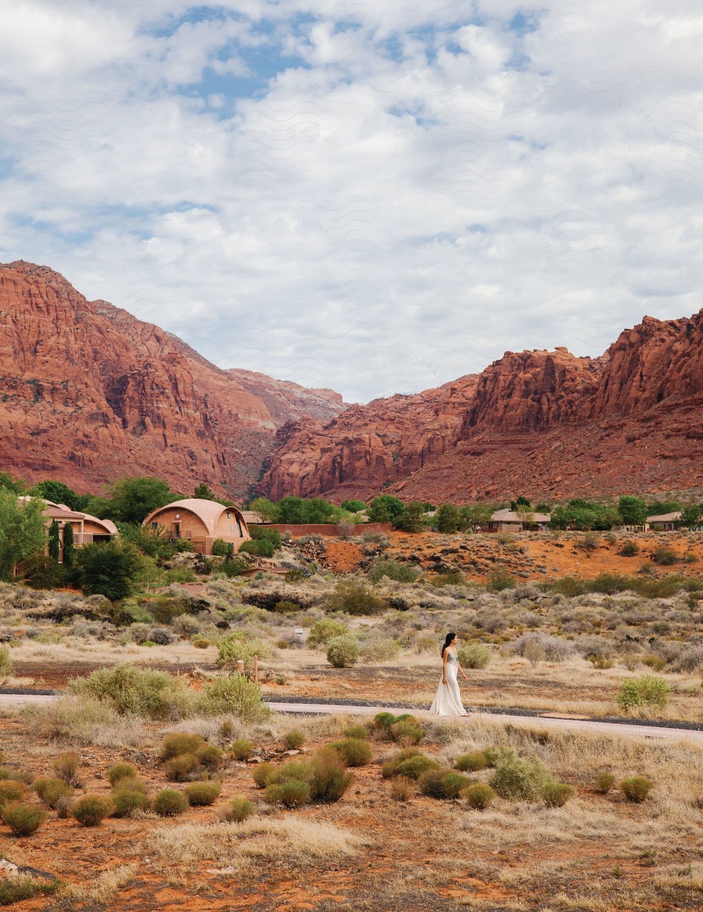 A woman walks down a path in a small town in the desert mountains