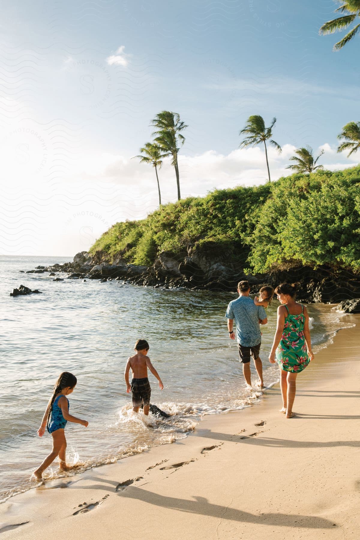 A family walking on the beach with trees in the background