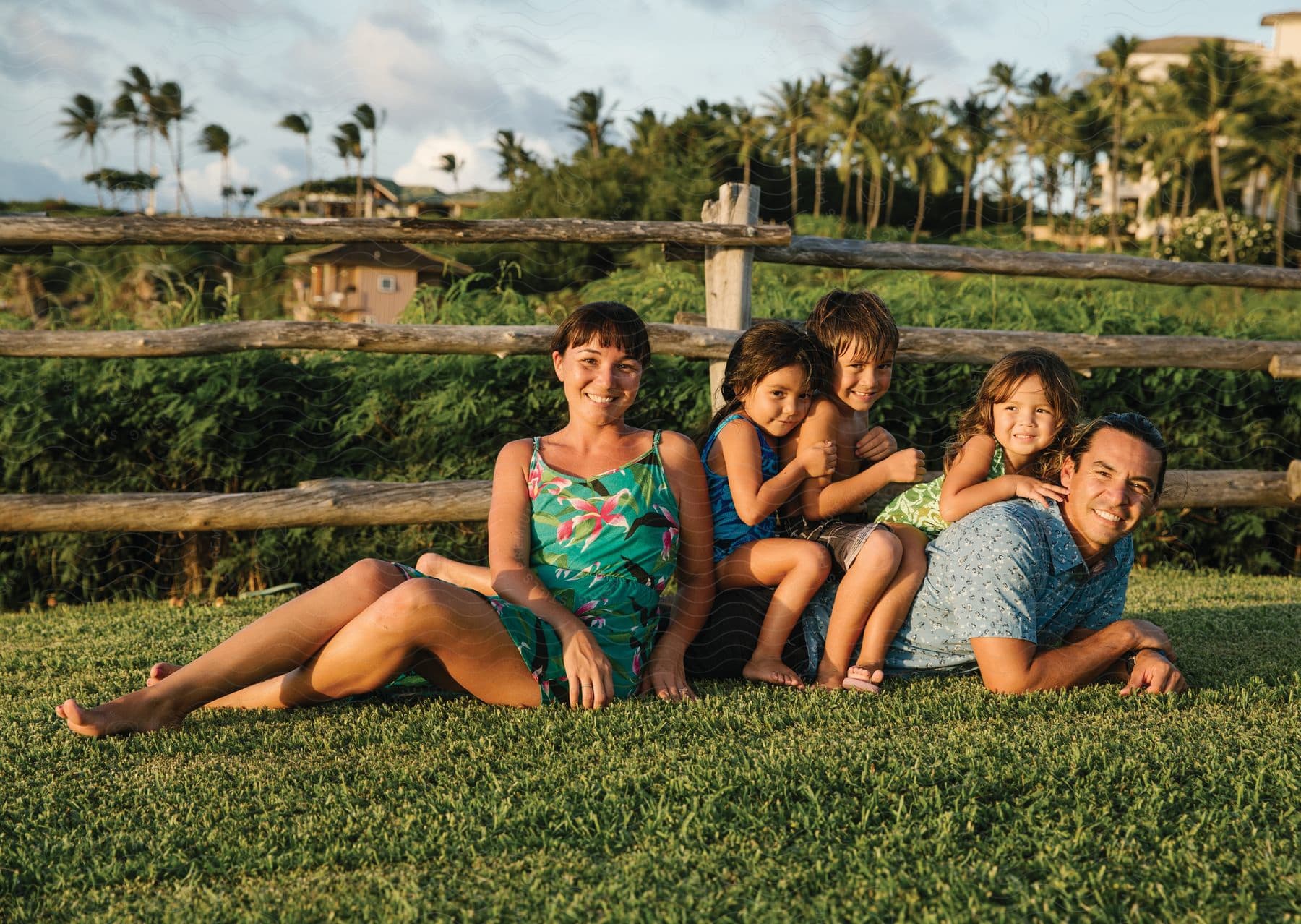 A family sitting on grass posing outdoors on a sunny day